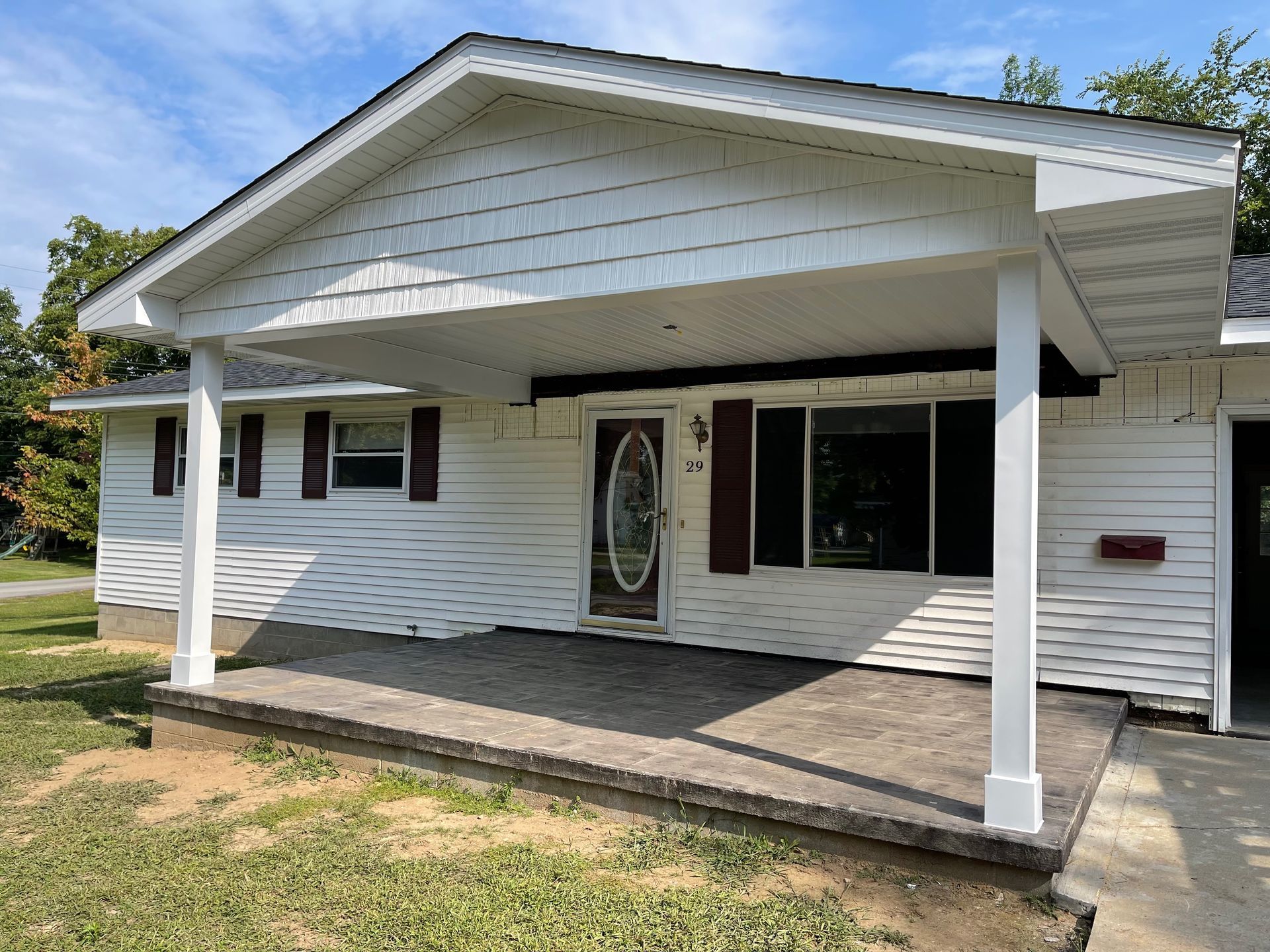 White house with covered porch and dark shutters.