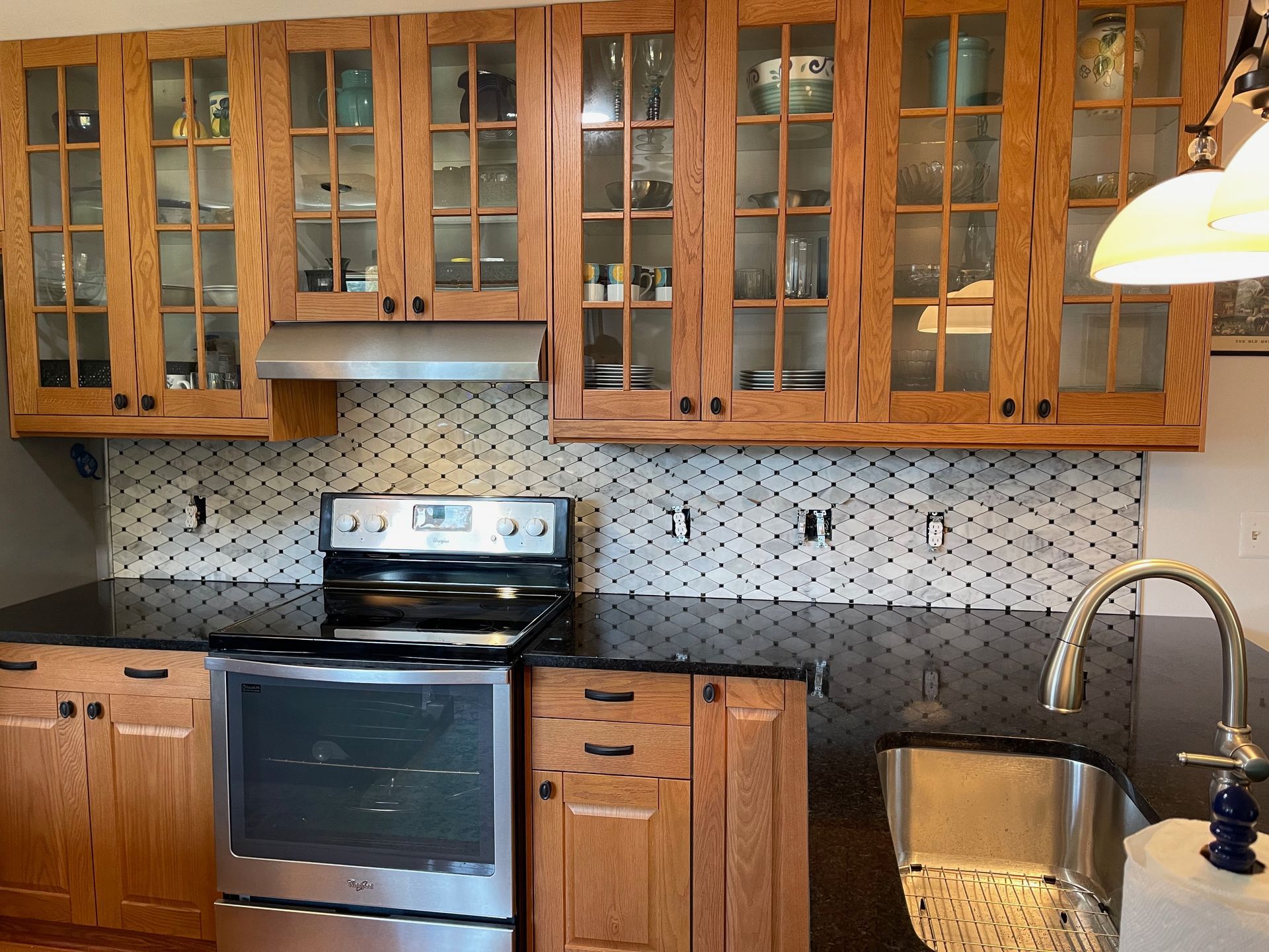 Kitchen with wooden cabinets, a black stovetop, and a stainless steel sink.