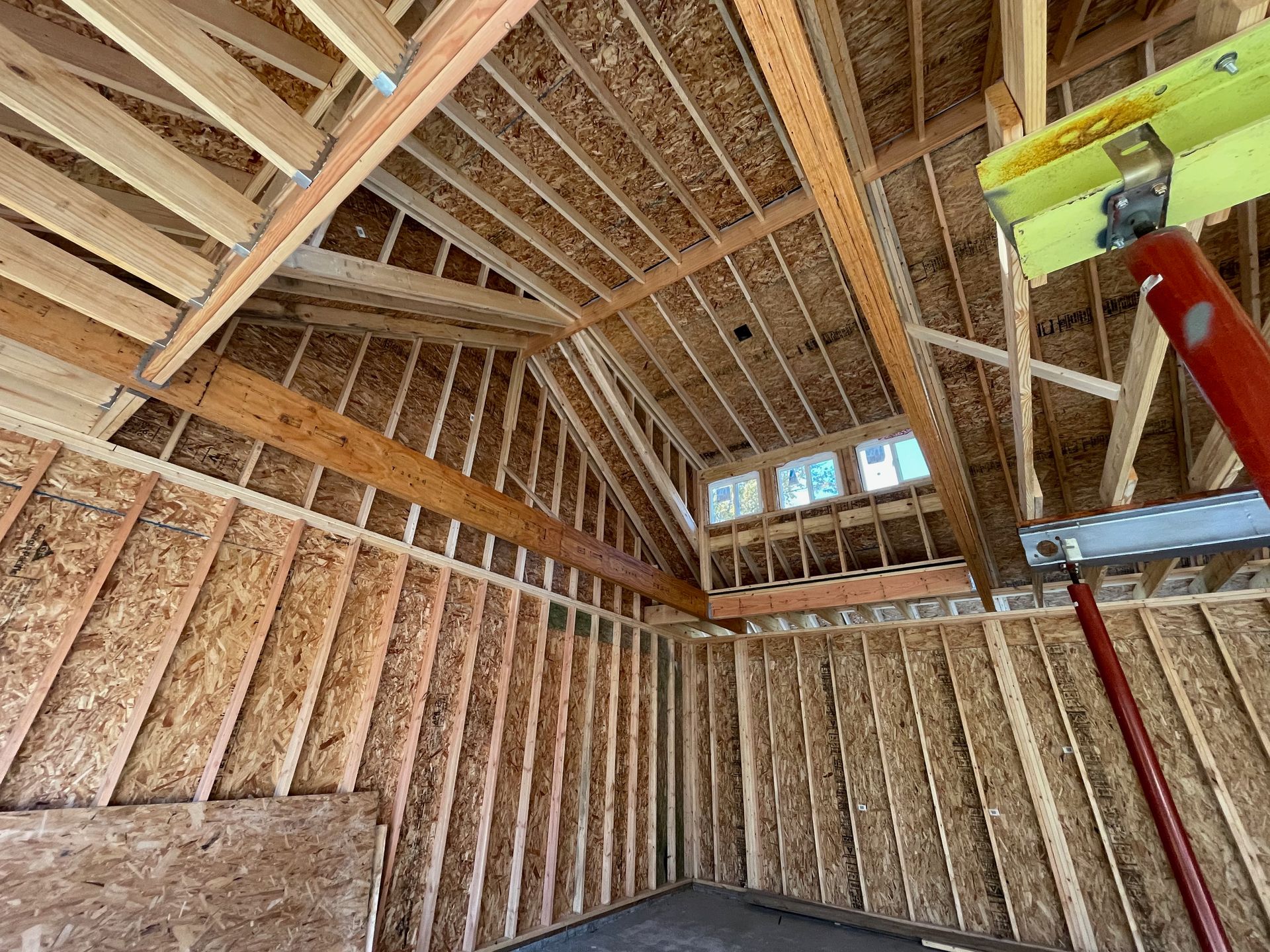 Interior view of a building under construction, showing wooden framework of walls, ceiling, and roof.