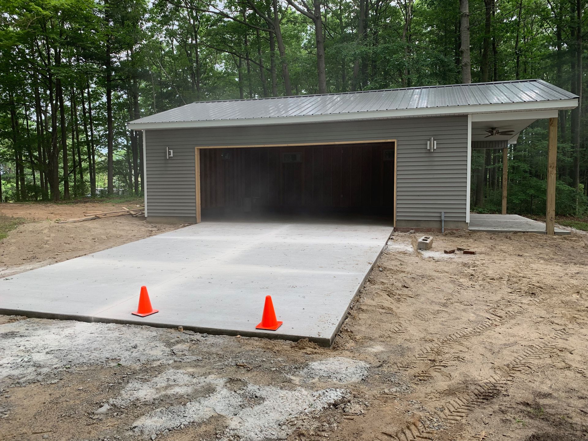 Newly built garage with concrete driveway and small covered carport.