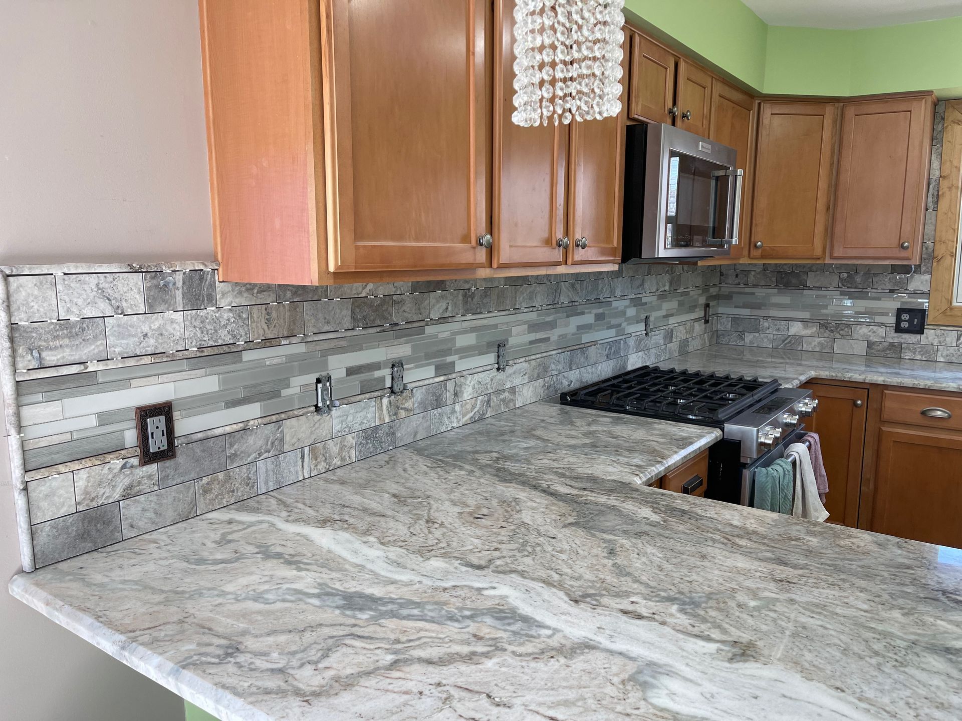 Kitchen with granite countertops, stone tile backsplash, and wooden cabinets.