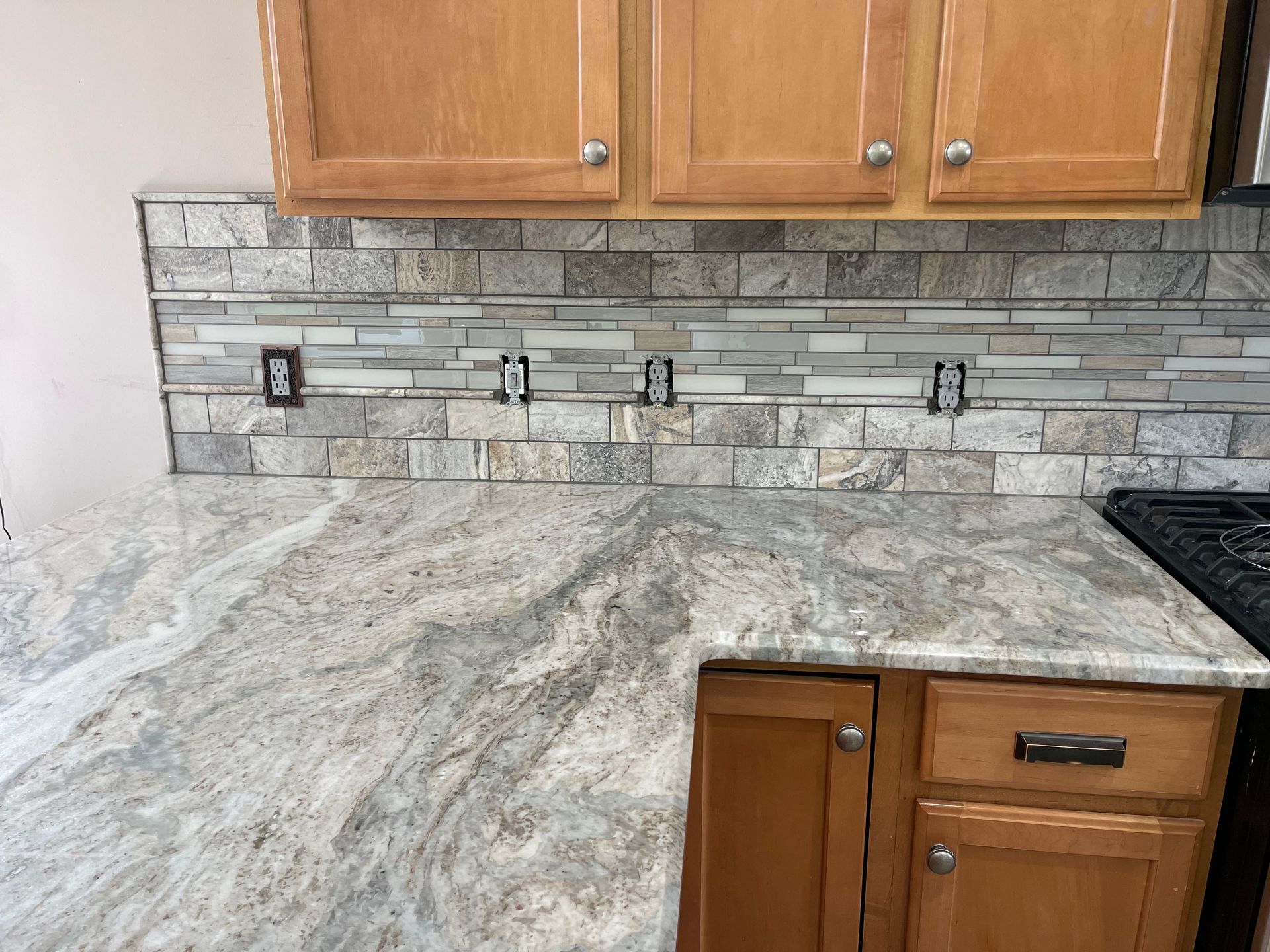 Kitchen with granite countertop, tiled backsplash, and wooden cabinets.