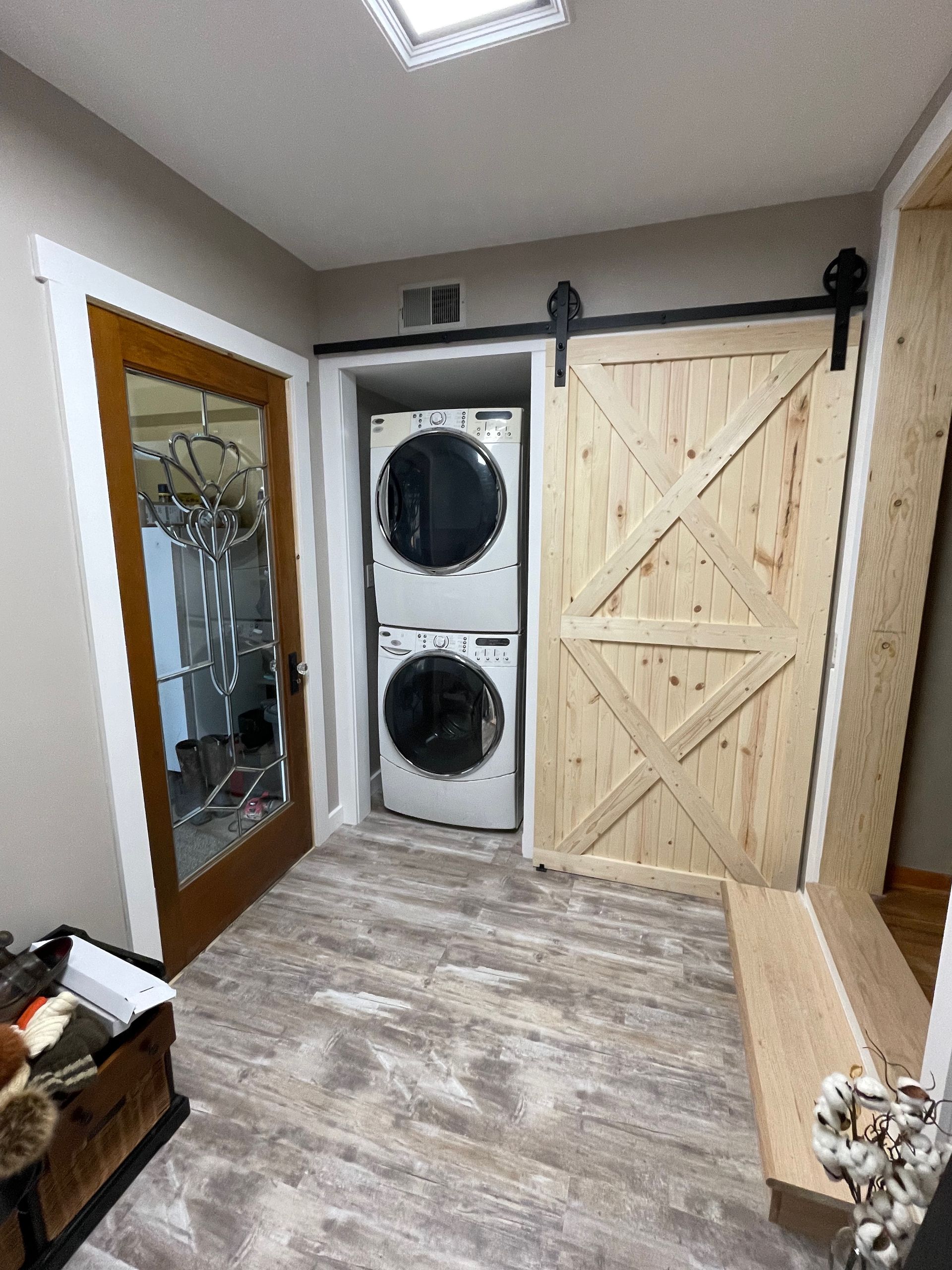 Laundry room with stacked washer/dryer, sliding barn door, and mirrored closet.