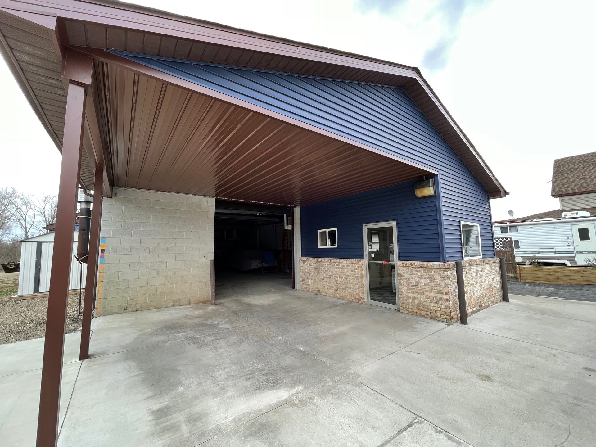 Building with blue siding, brown awning, and concrete driveway.