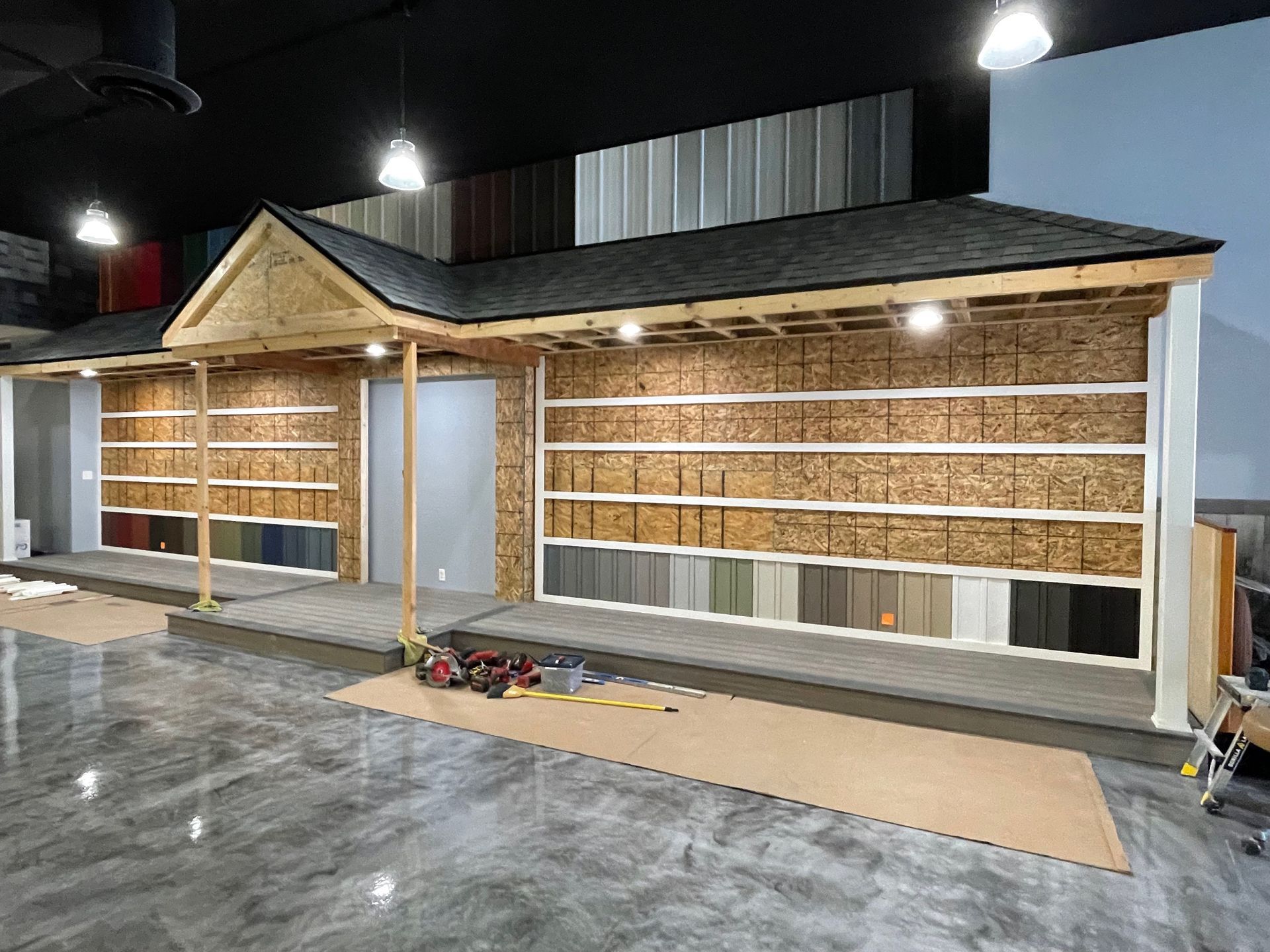 Display of roofing and siding samples in a showroom, built like a small house, with lighting.