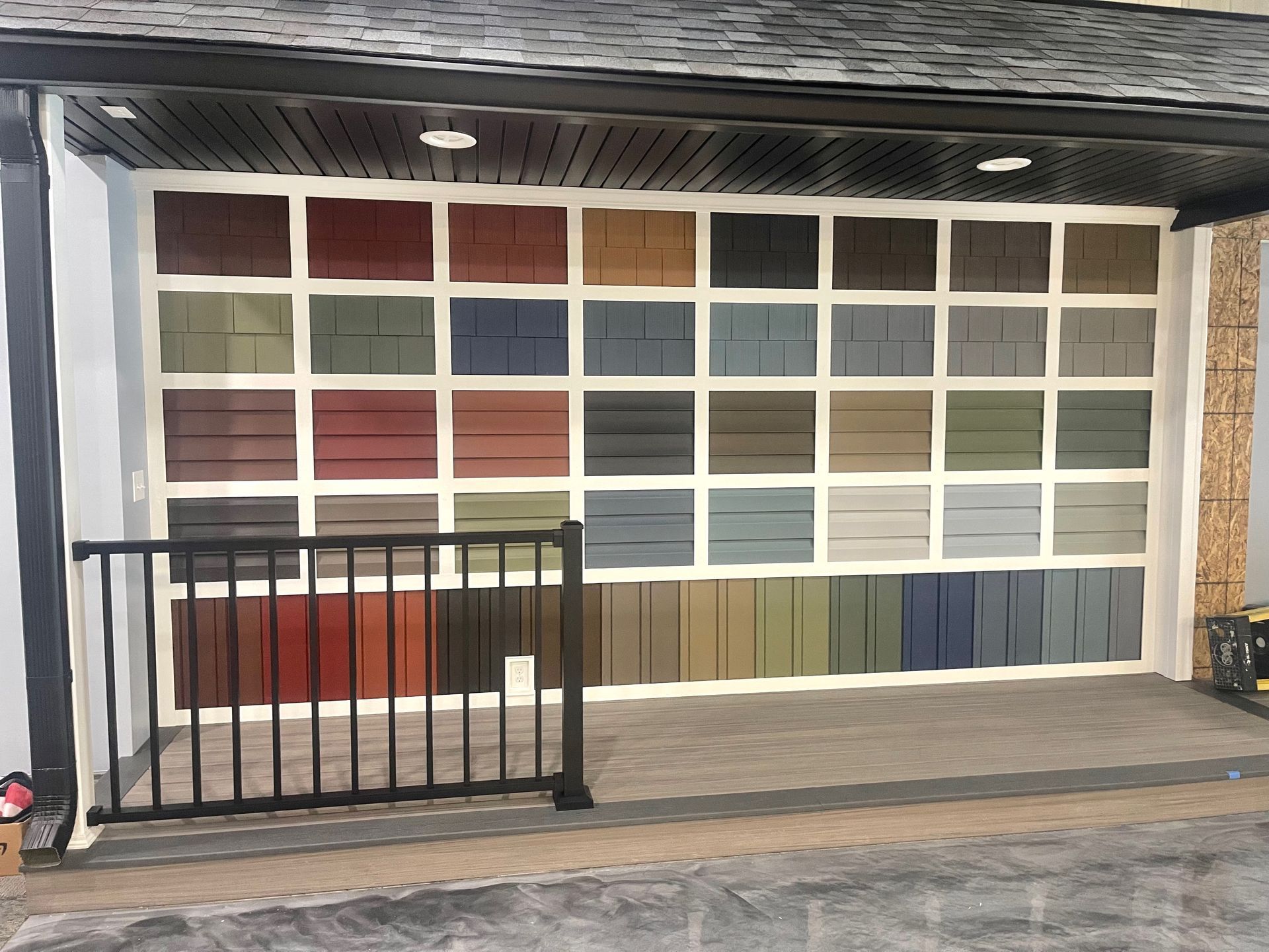 Display of siding color samples arranged in a grid with a railing in the foreground.