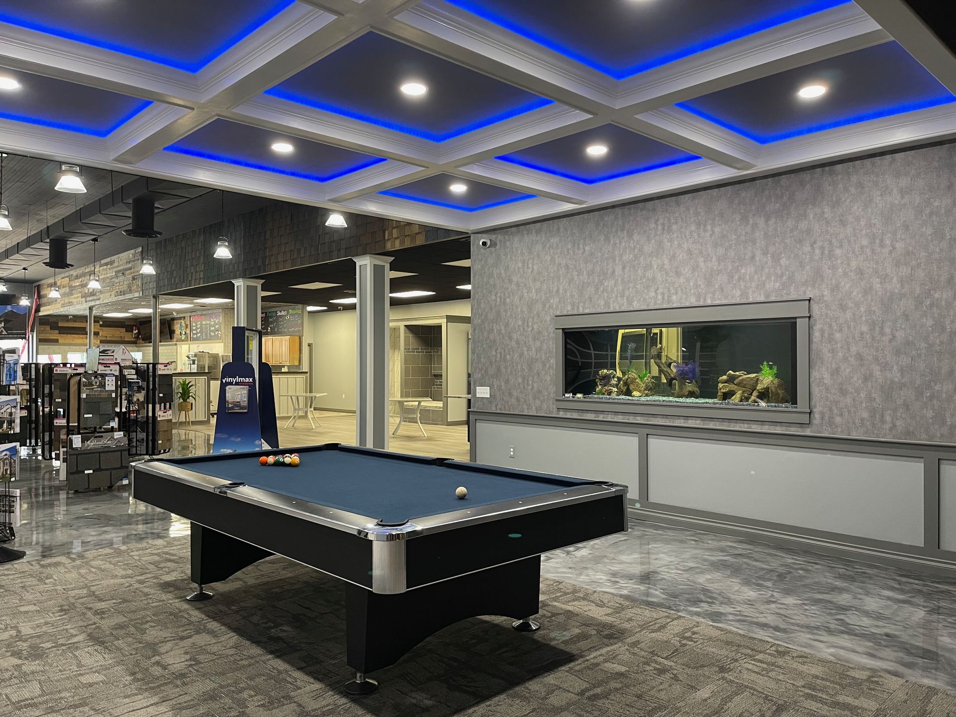 Pool table in a room with a large aquarium, recessed ceiling lights, and patterned wallpaper.