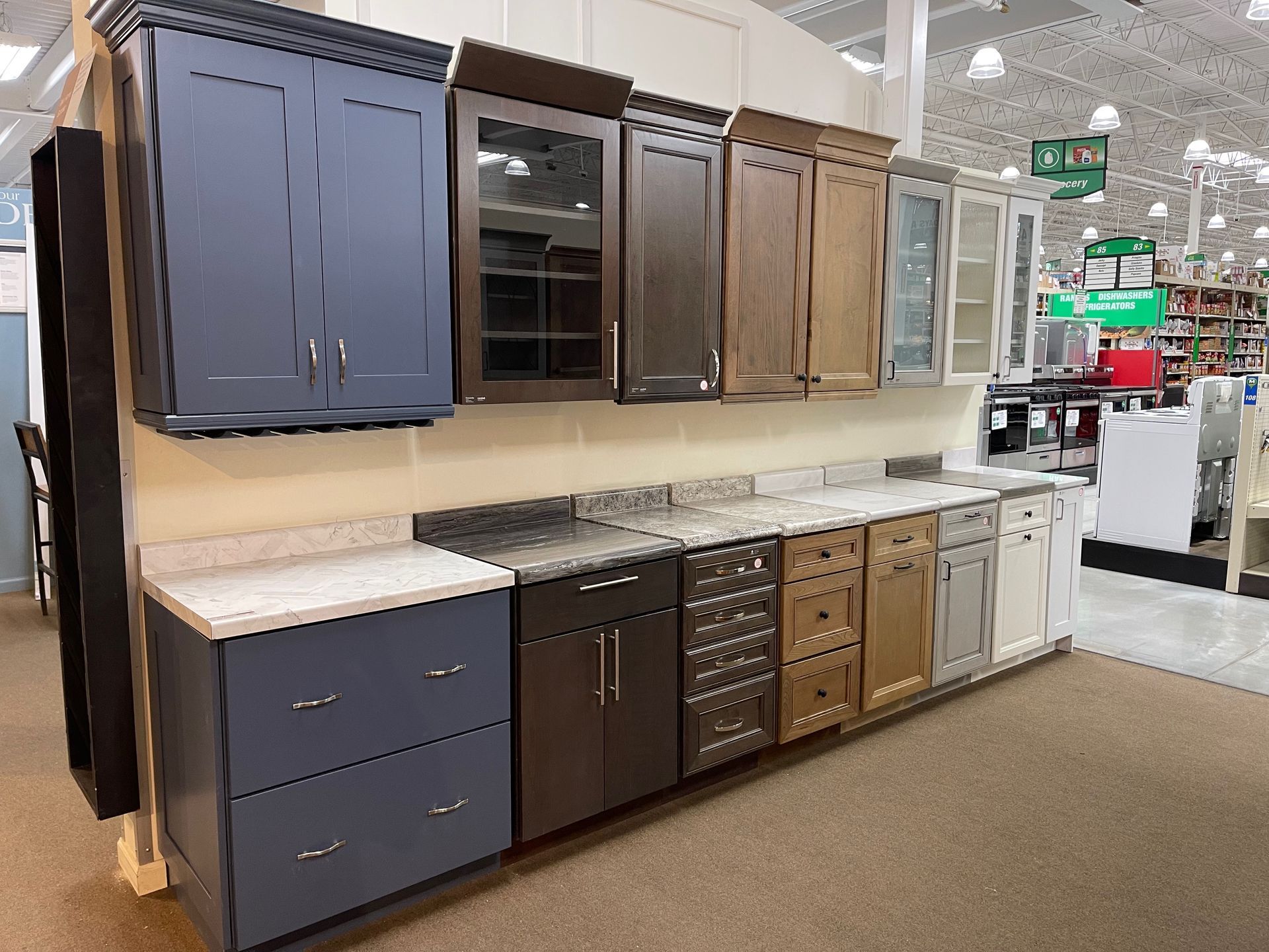 Kitchen cabinets and countertops displayed in a store. Various colors and styles are shown.