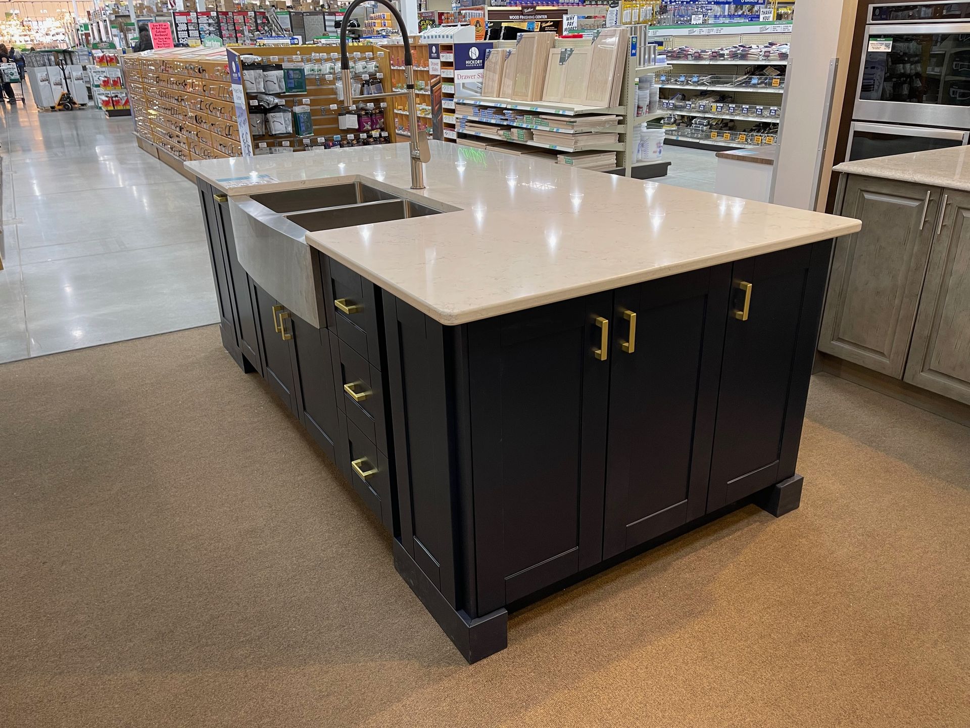 Kitchen island with a dark blue base, white countertop, stainless steel sink, and gold hardware.