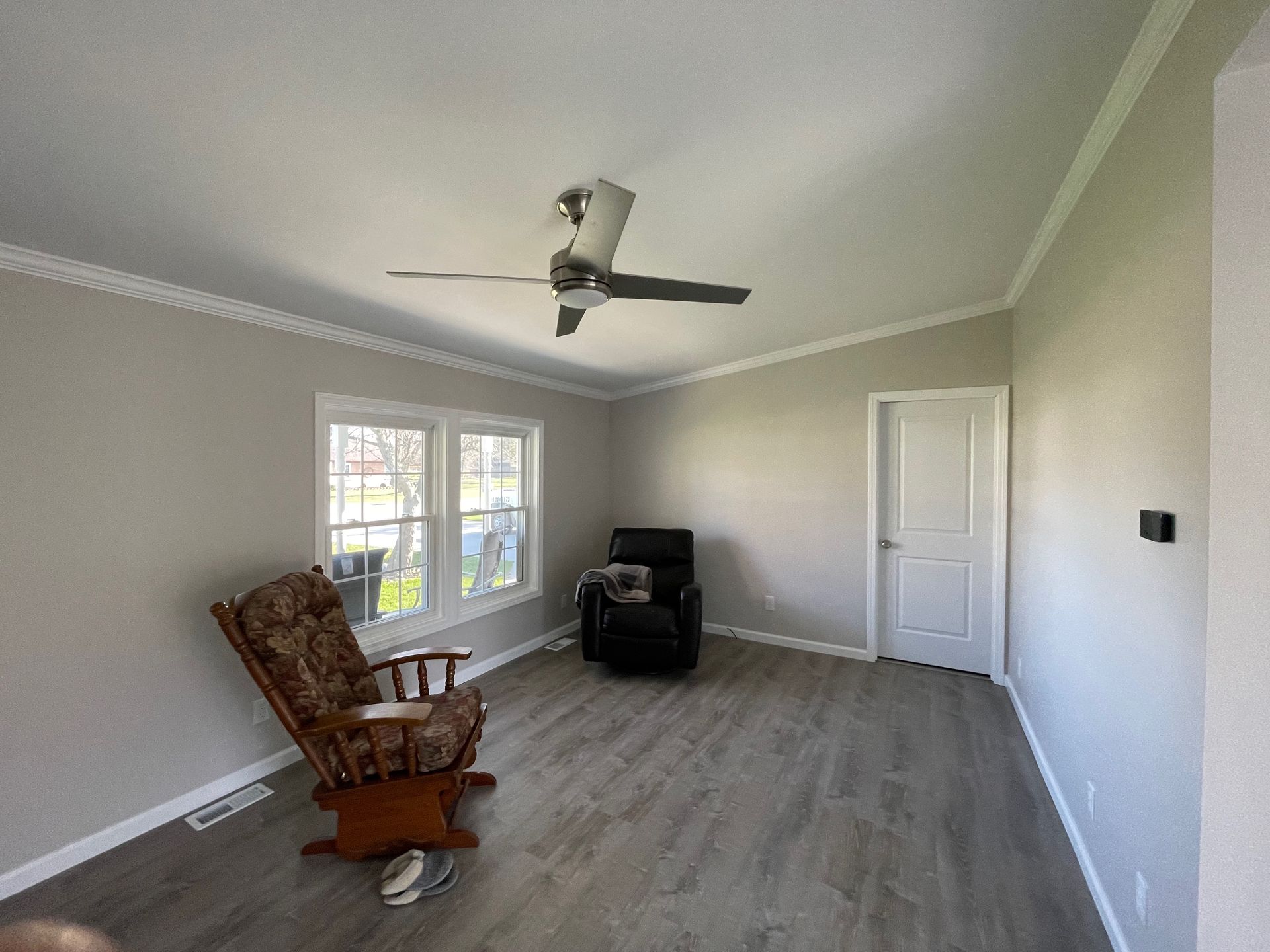 Living room with gray walls, light gray floor, ceiling fan, and two armchairs.