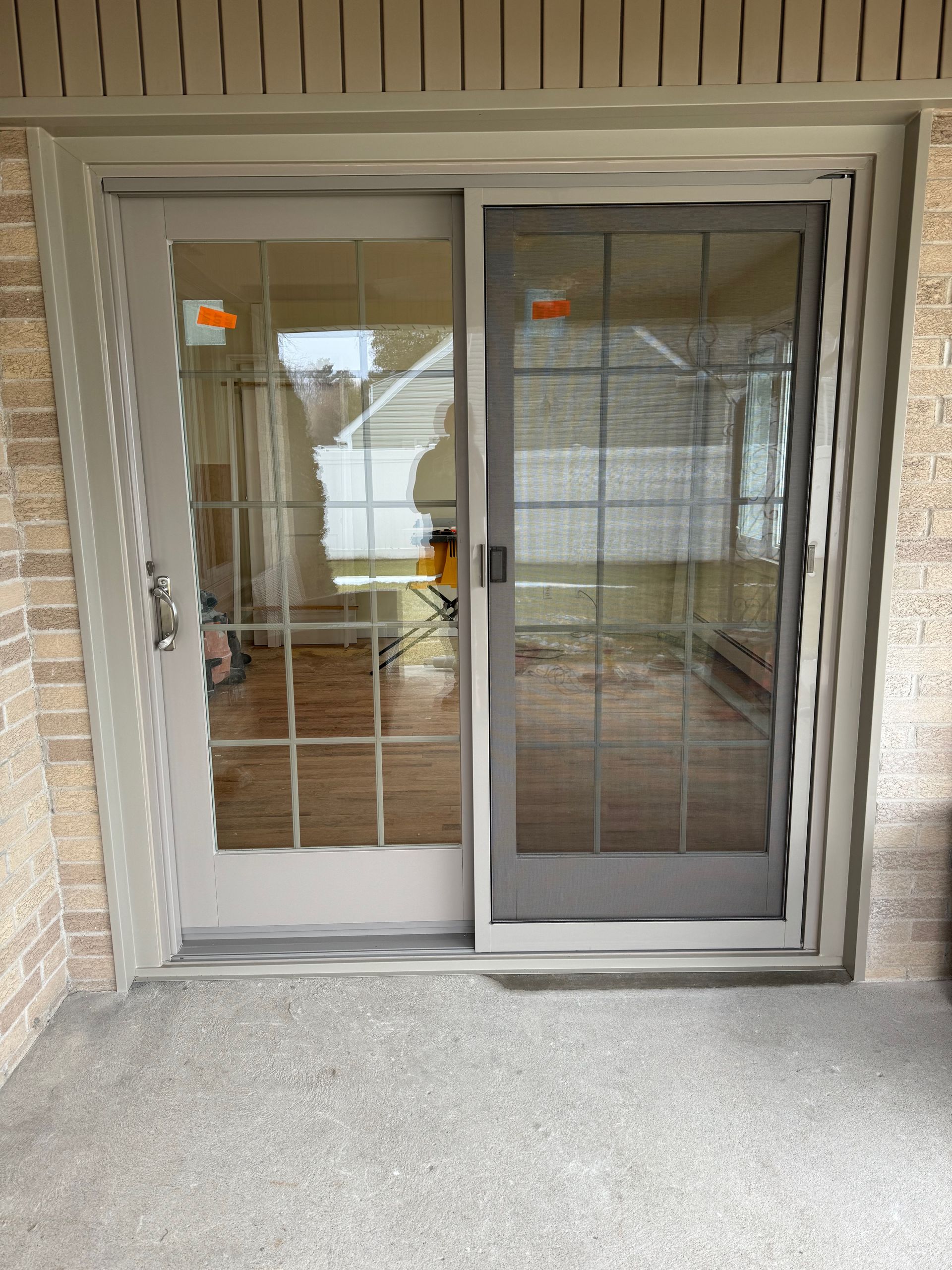 Sliding glass patio doors, with gray frames, on a concrete patio, exterior of a home.