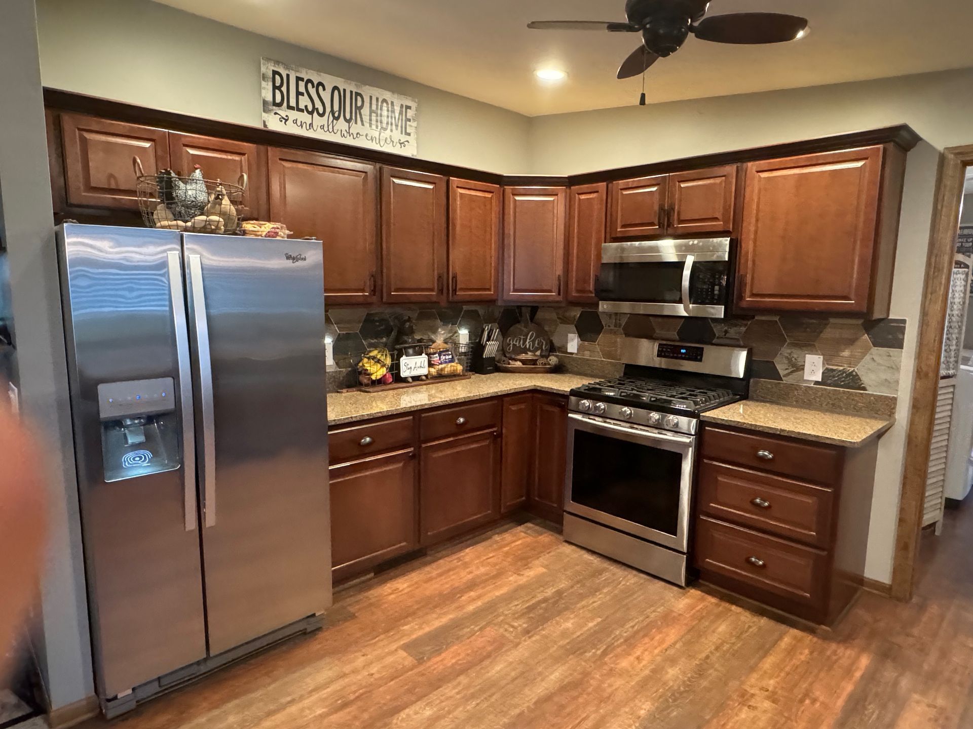 Kitchen with dark wood cabinets, stainless steel appliances, and stone backsplash.