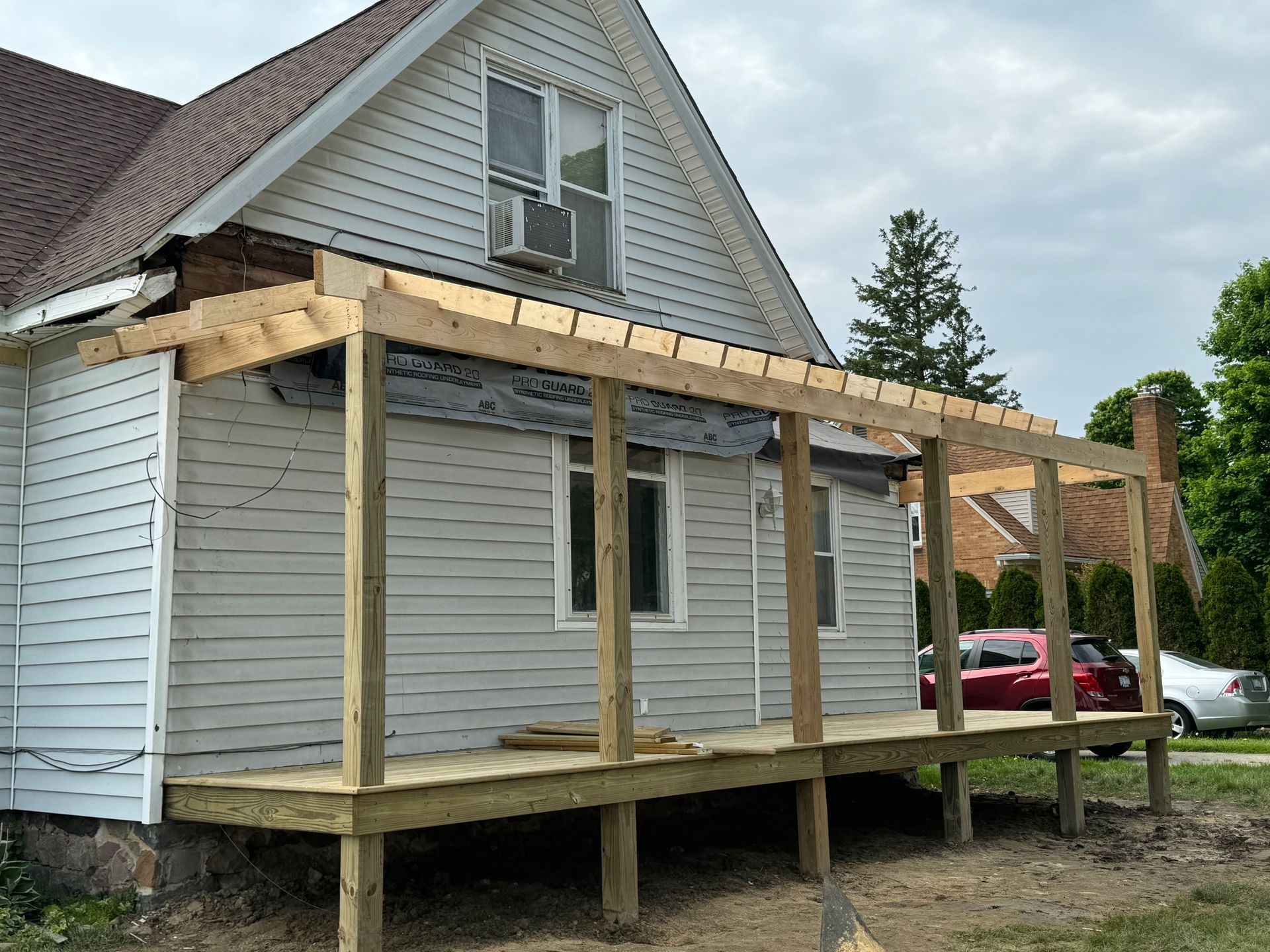 Wooden porch under construction on a light gray house.