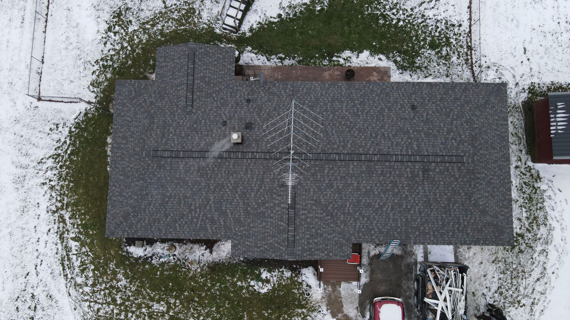 Overhead view of a house with a snow-covered roof and surrounding yard.