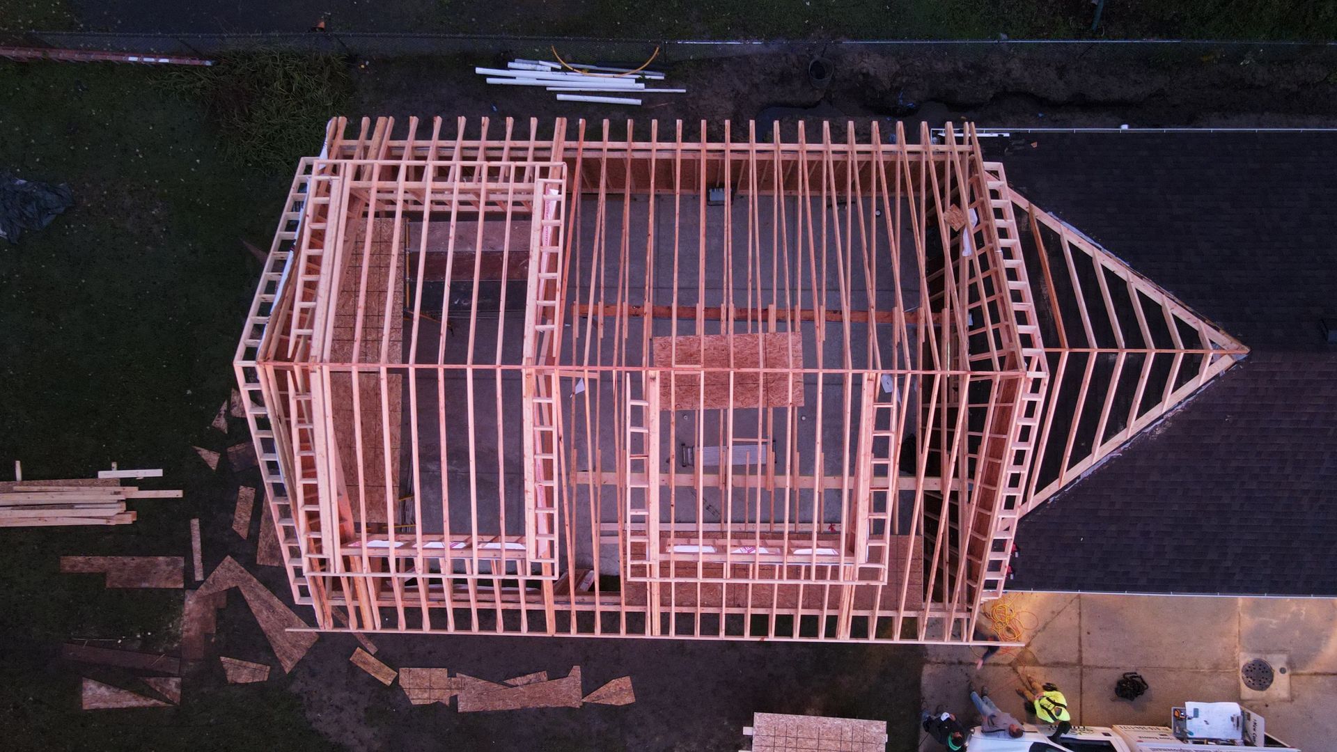 Overhead view of a house under construction; wooden frame and roof structure visible.