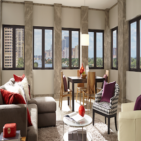 Bright living room with large windows, sofa, chairs, and dining table overlooking a city view