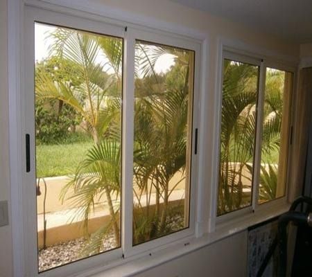 Sliding window with white frames overlooking a palm-lined garden and walkway.