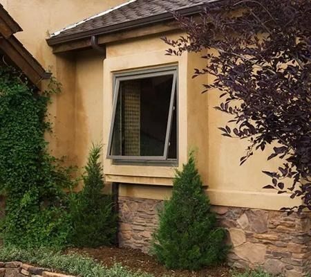 House exterior with beige stucco, stone trim, open window, and shrubs in the foreground