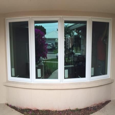 Curved bay window with white frames reflecting a street and greenery