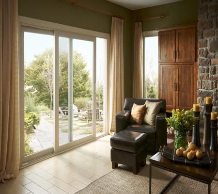 Sunlit living room with large sliding glass doors, leather chair, and wooden accent wall
