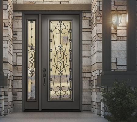 Front entrance with dark double doors, ornate glass panels, stone facade, and a lit wall lantern.