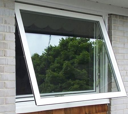 Partially open white-framed window on a brick house, reflecting trees outside