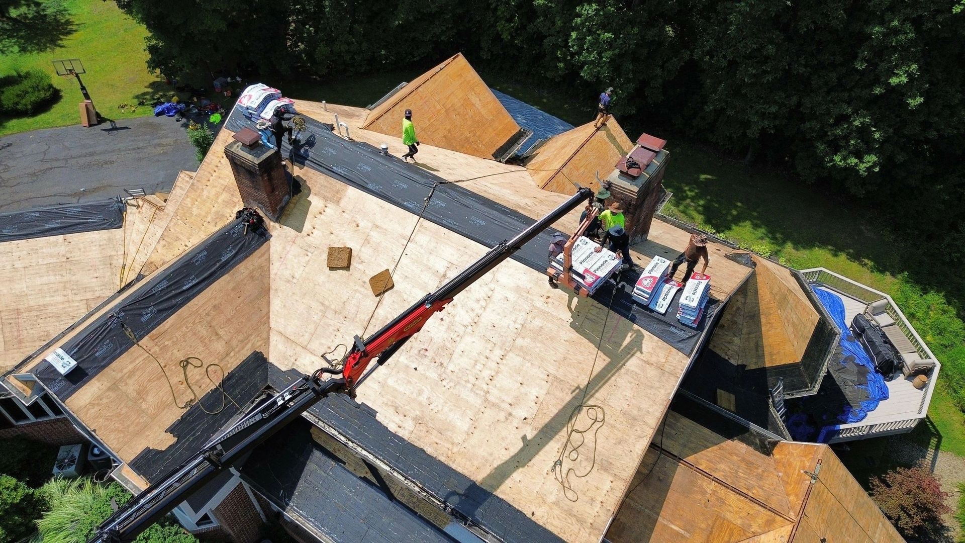 An aerial view of a roof being installed on a large house.