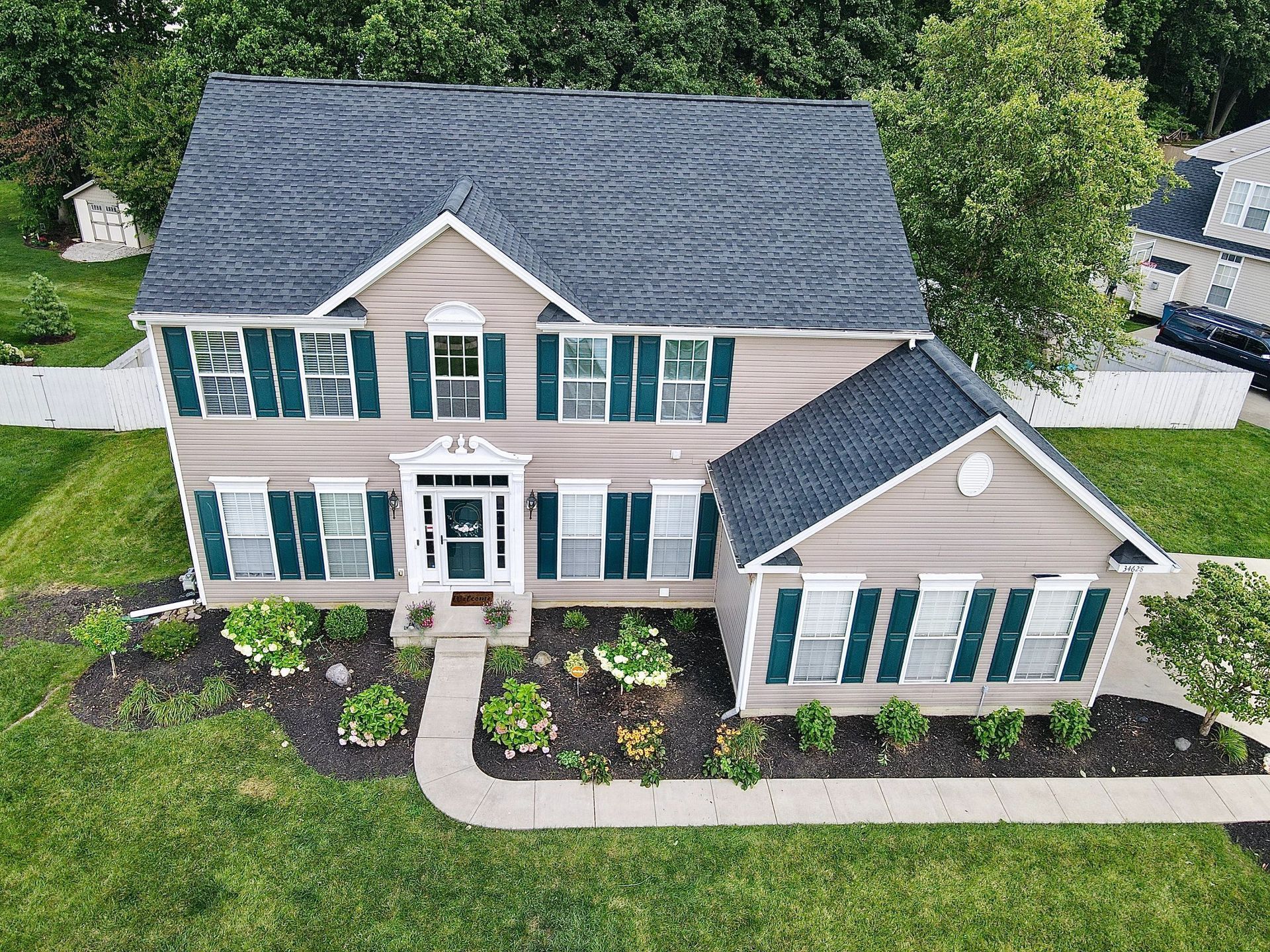 An aerial view of a large house with a blue roof and green shutters.