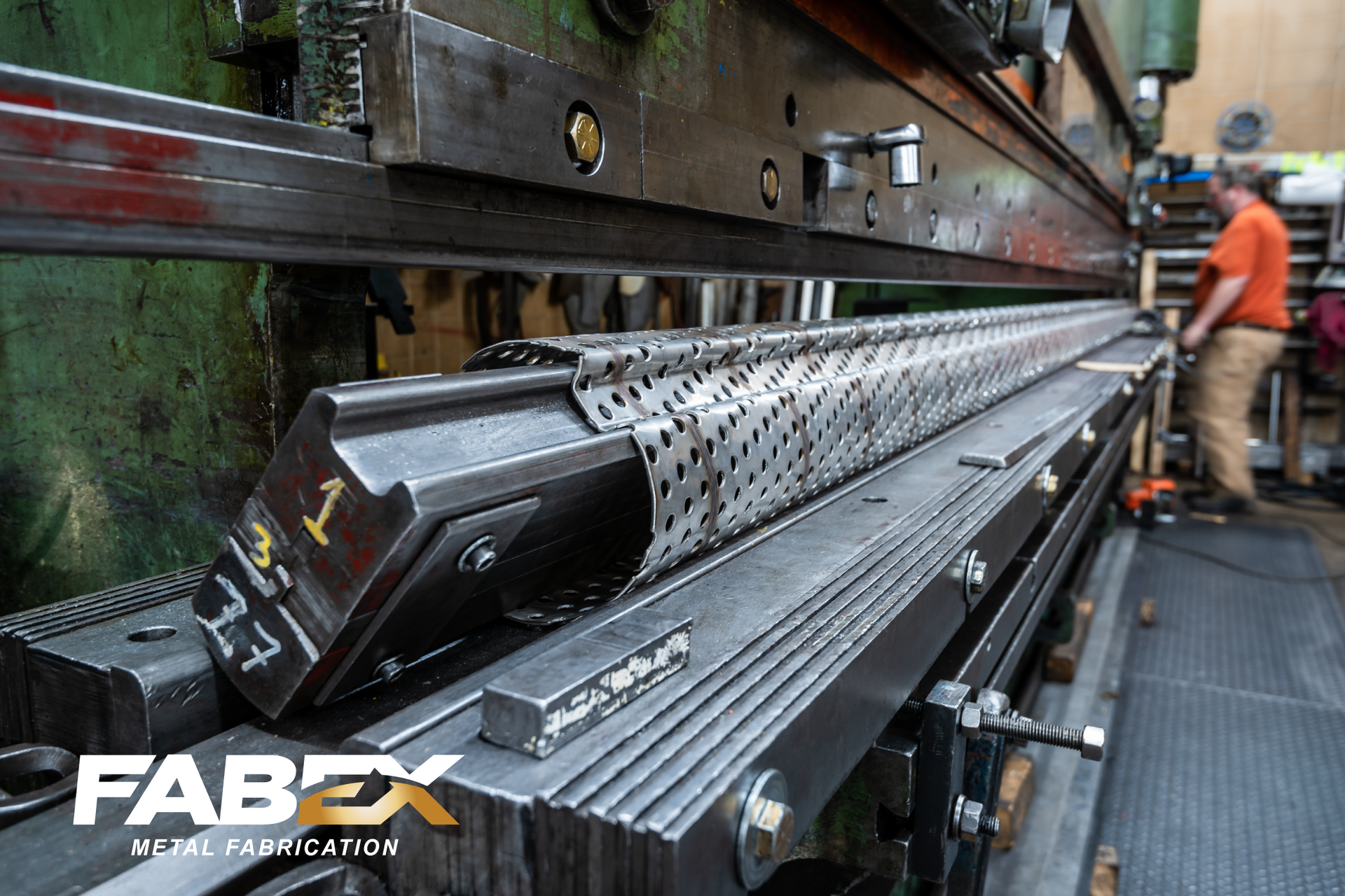 Metal rail conveyor with a worker in an industrial setting, FABEX logo visible.