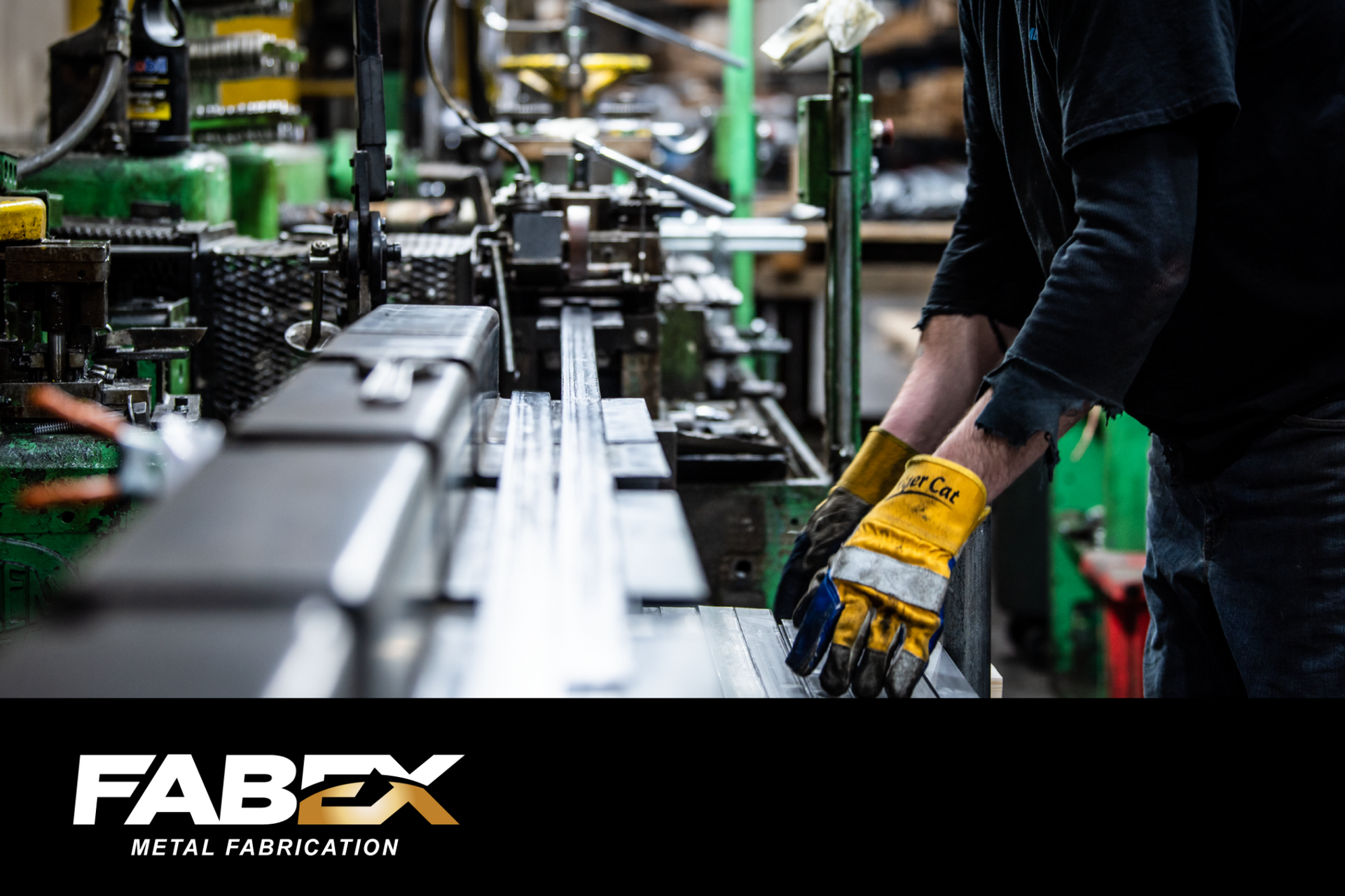 Factory worker wearing yellow gloves operating machinery on an industrial production line.