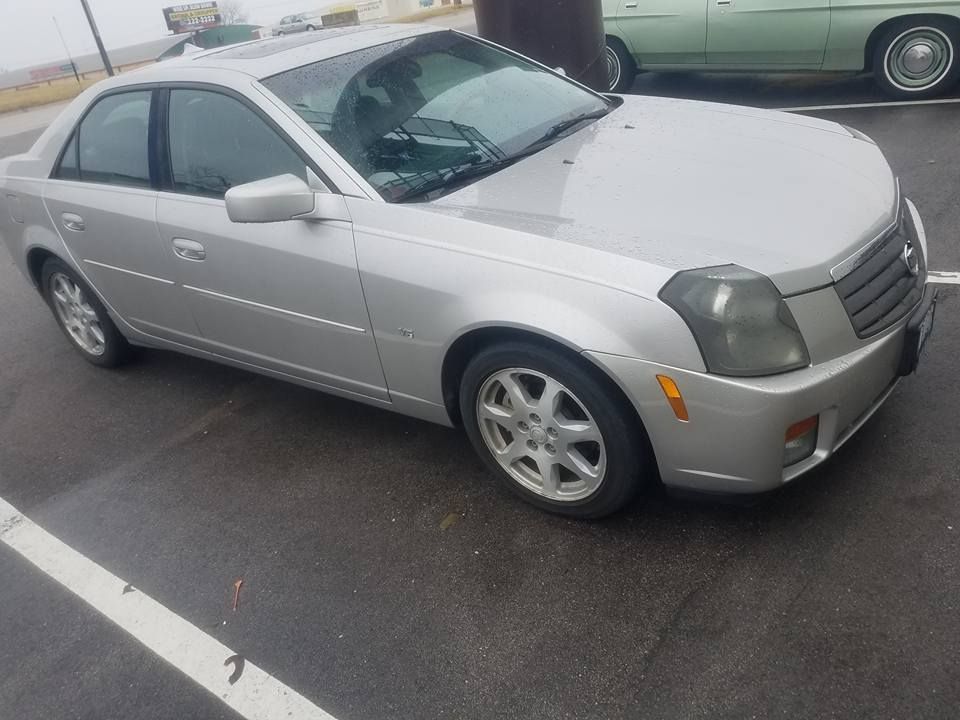Silver Cadillac CTS sedan parked on wet asphalt.