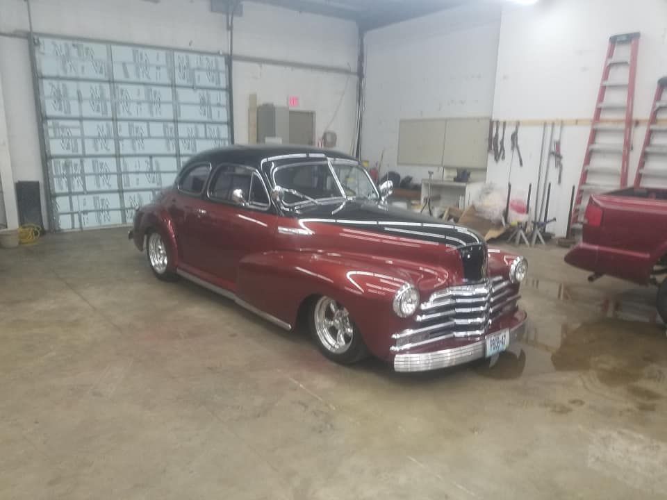 Burgundy and black vintage car in a garage.