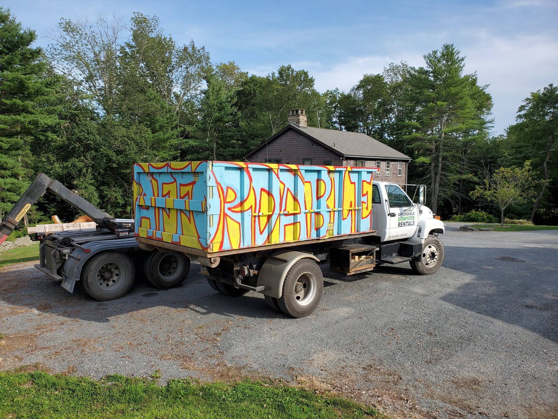 A dump truck with graffiti on the side is parked in front of a house.
