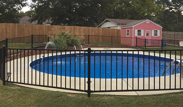 Backyard pool with black fence and a pink shed in the background