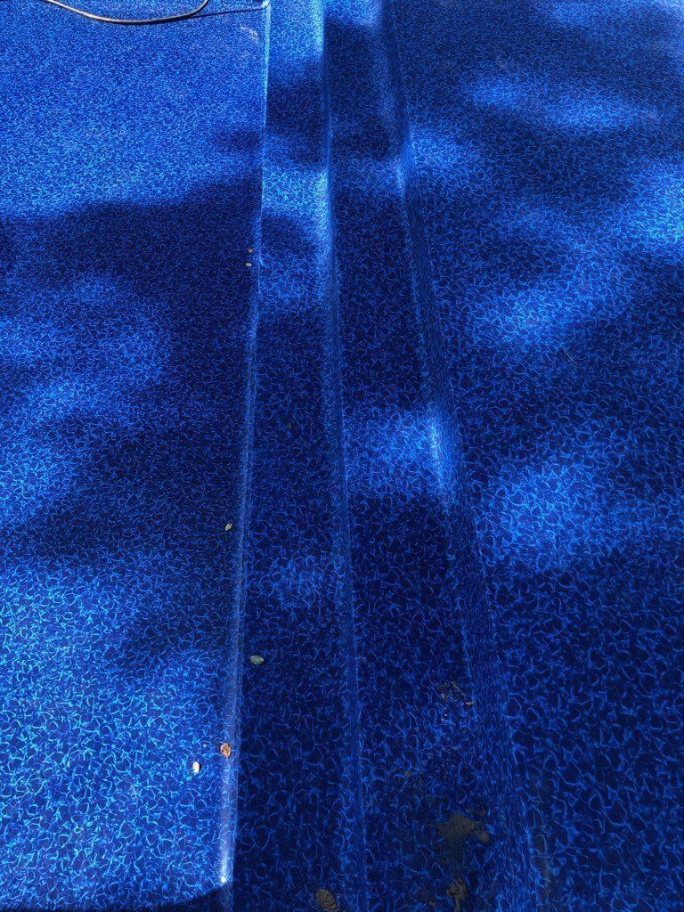 Narrow blue-lit corridor with a dark central strip and textured walls, viewed from above.