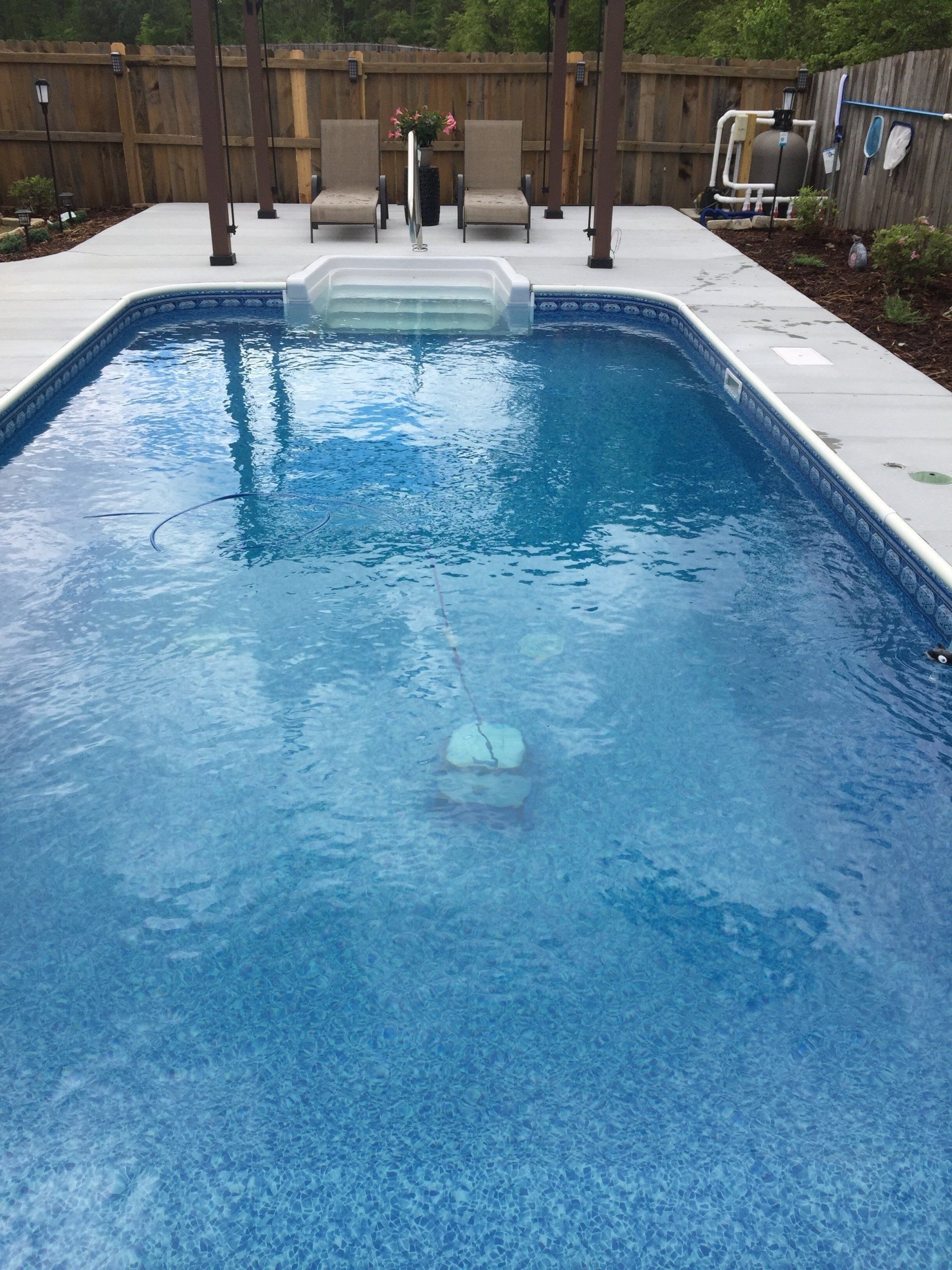Backyard swimming pool with a fountain and diving board, viewed from the shallow end.