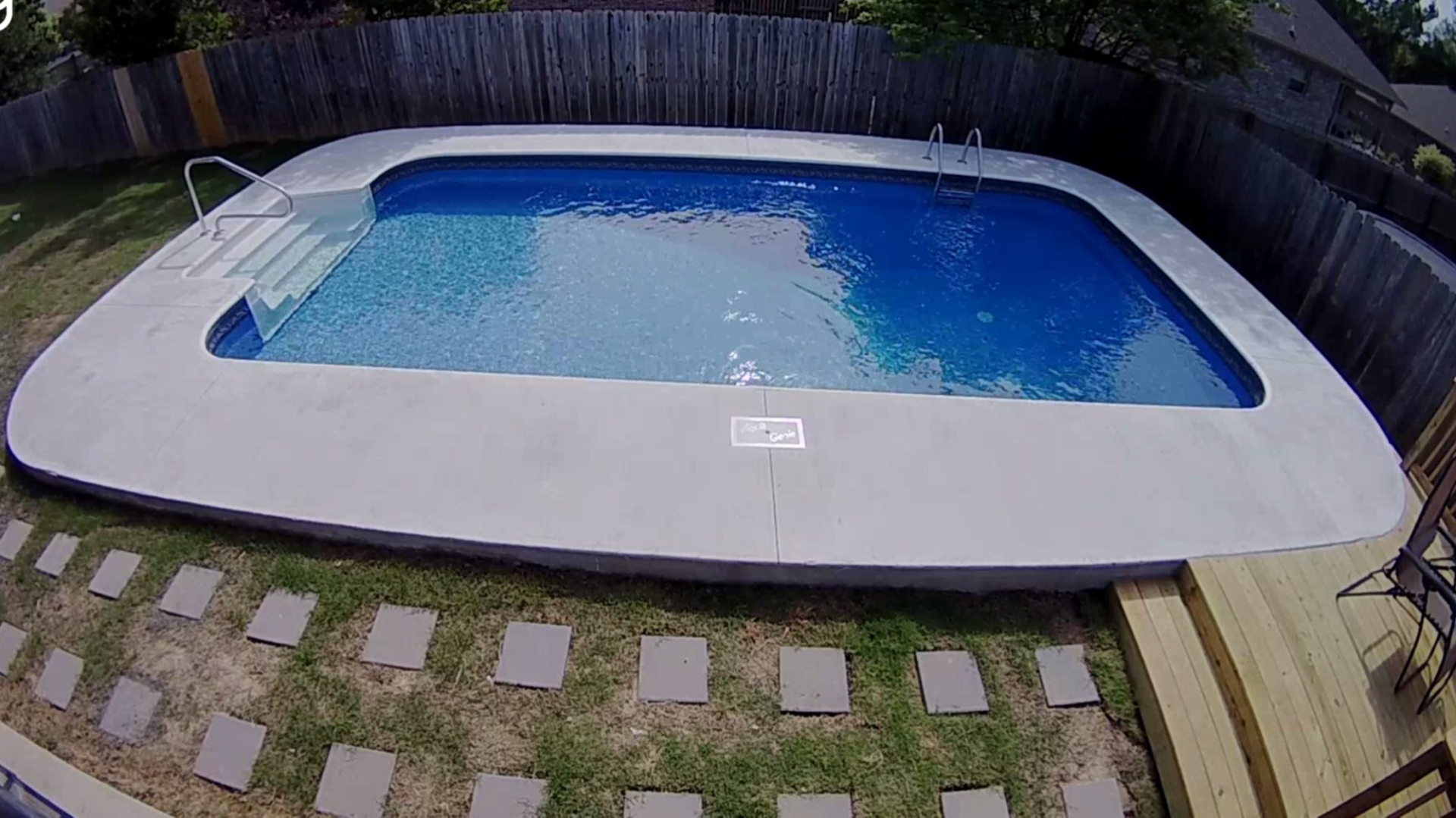 Backyard swimming pool with bright blue water, white coping, and a stone path in front