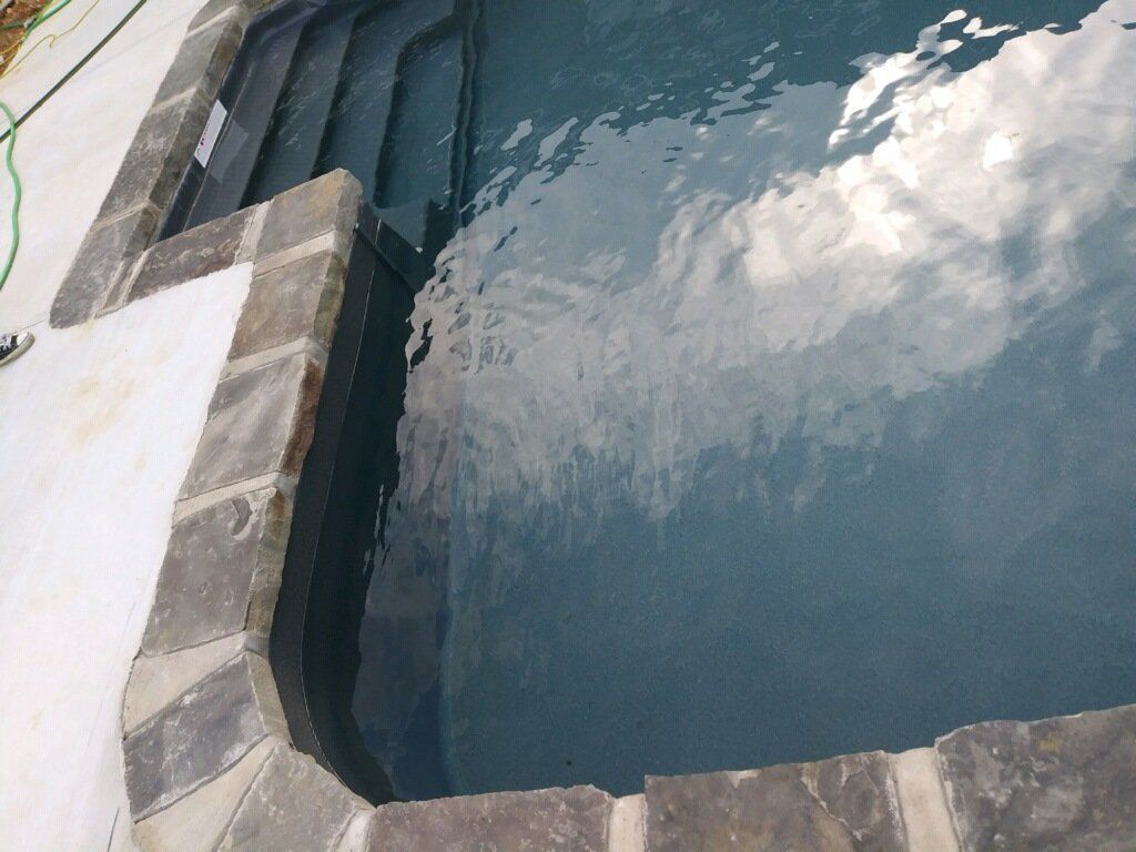 Blue swimming pool with stone edge and water reflections