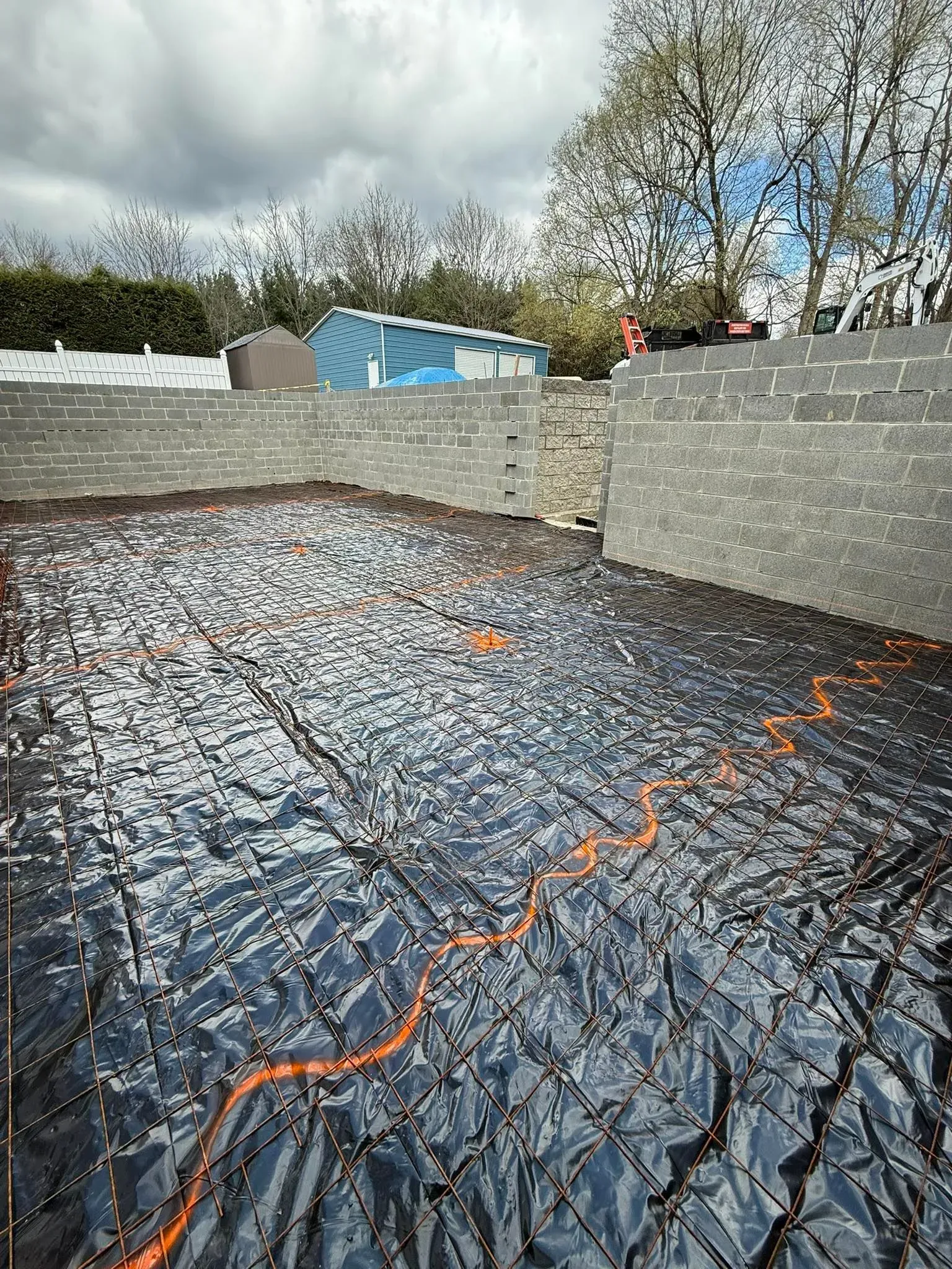 Black and silver material on a construction site, with stone walls and a cloudy sky.