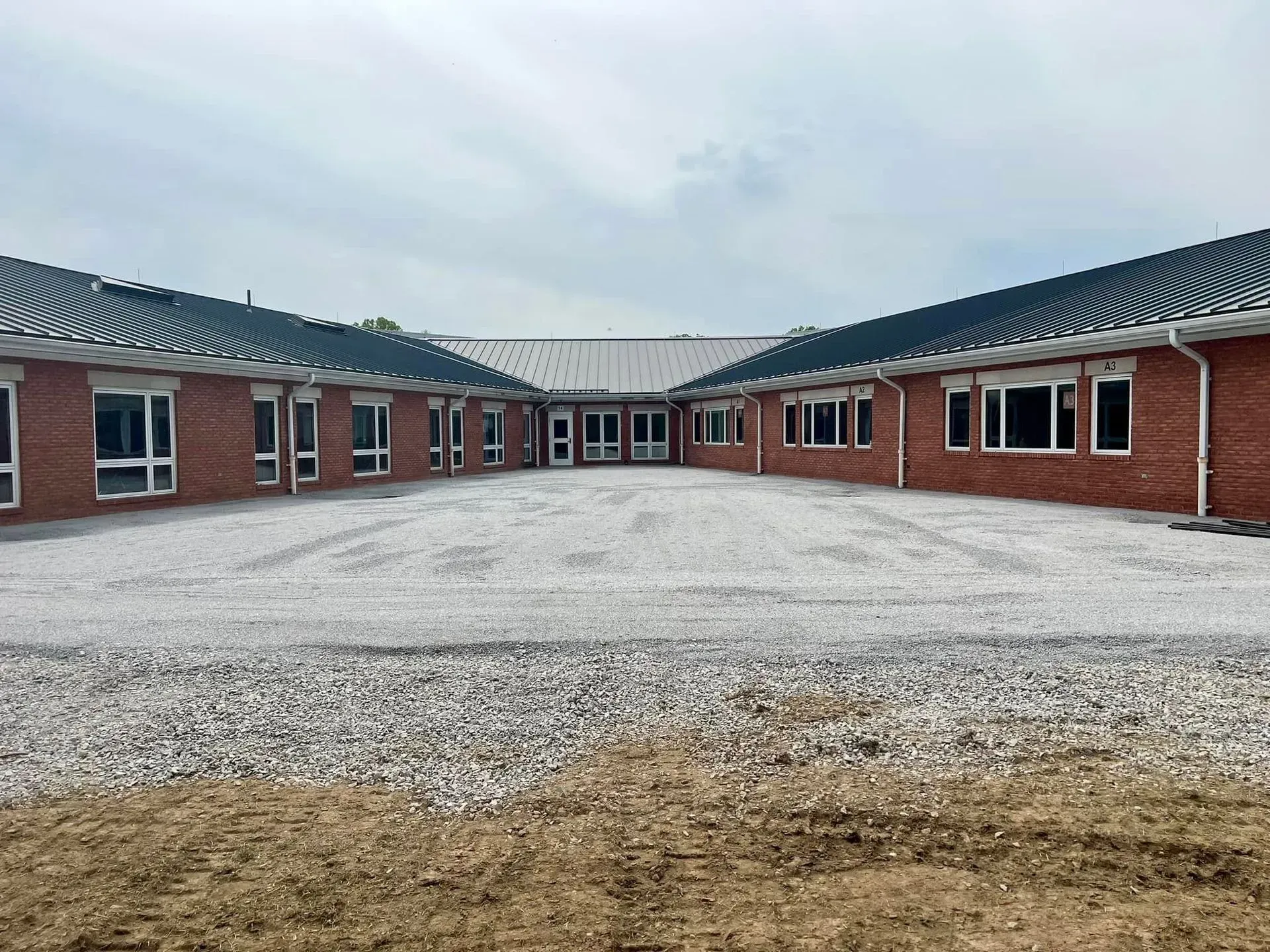 Red brick building with a central courtyard, light gravel surface.