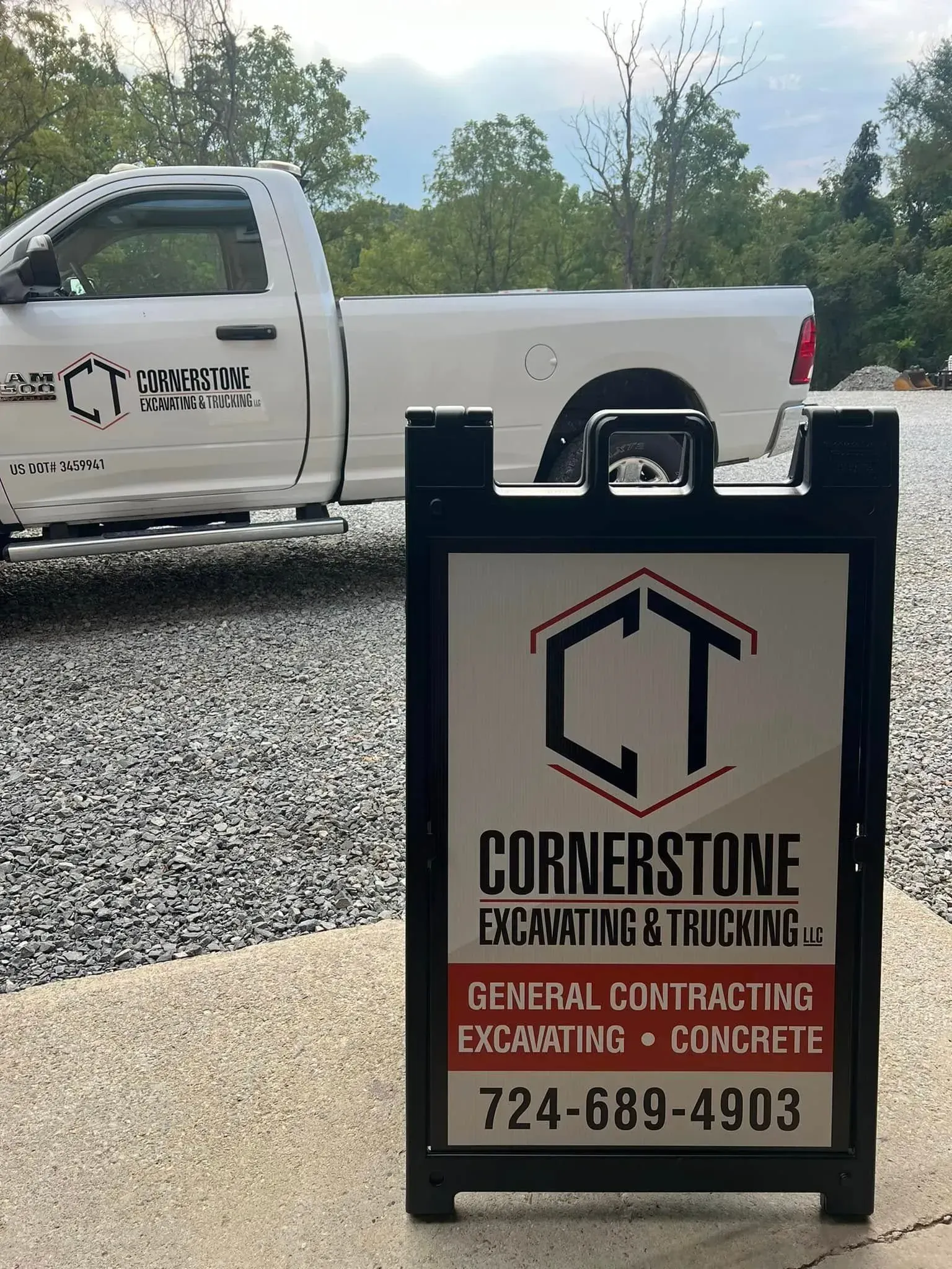 A sign for Cornerstone Excavating & Trucking LLC with a white truck in the background.
