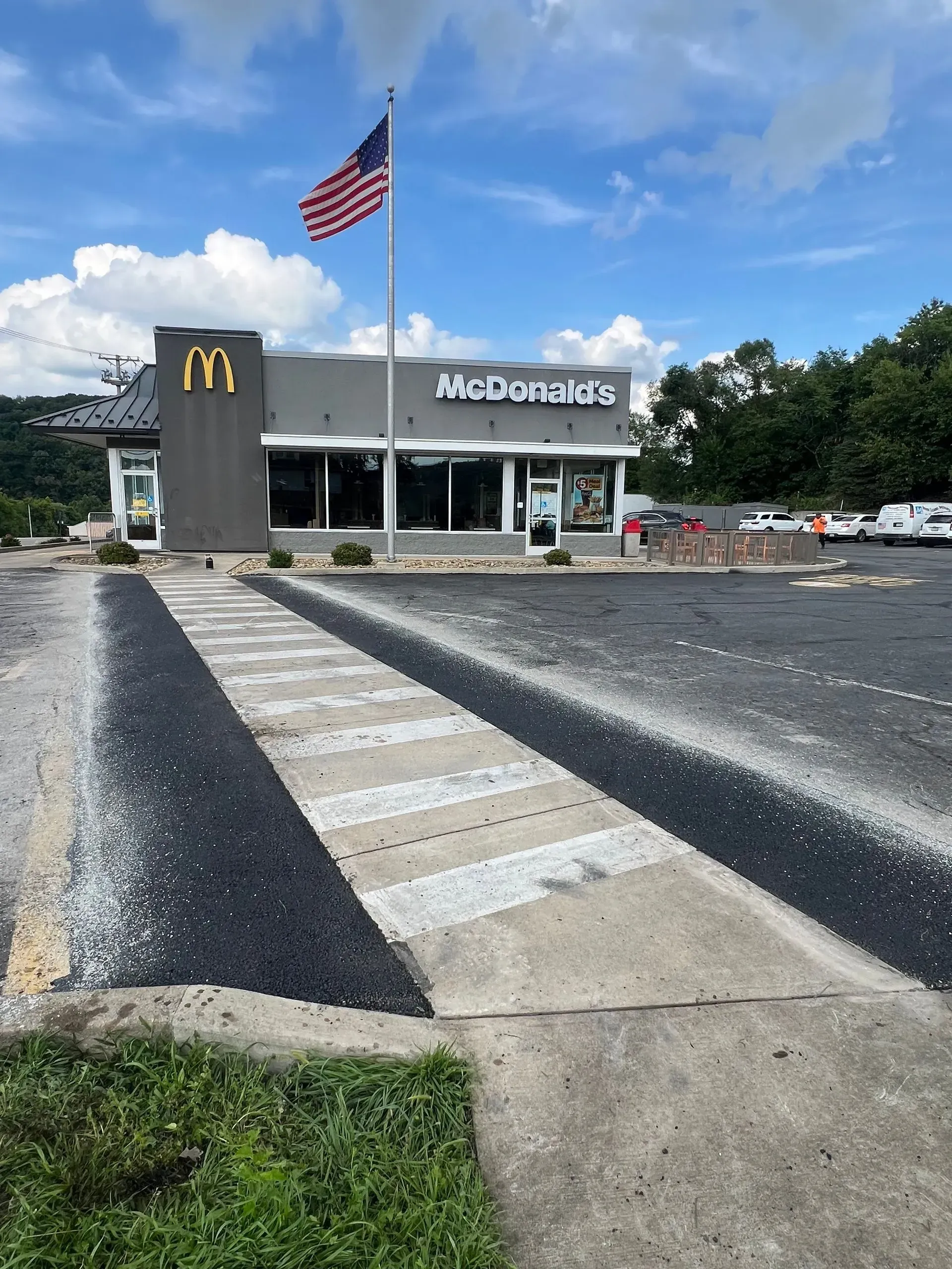 McDonald's restaurant with the American flag. Crosswalk in front. Cloudy sky overhead.