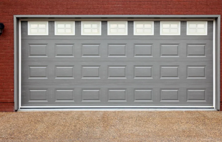 Gray garage door with windows, set in brick.