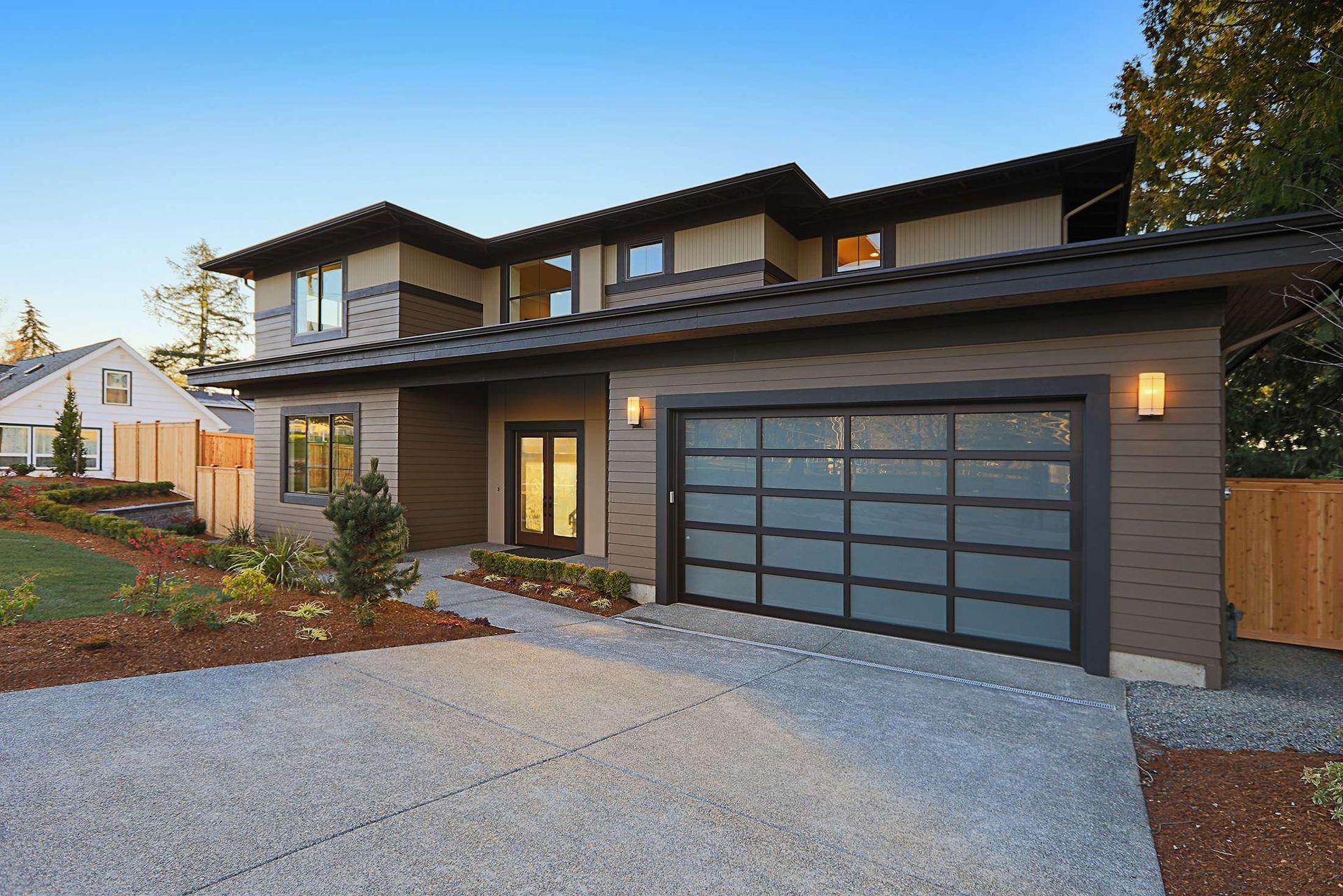 Modern home exterior with a glass garage door and concrete driveway.