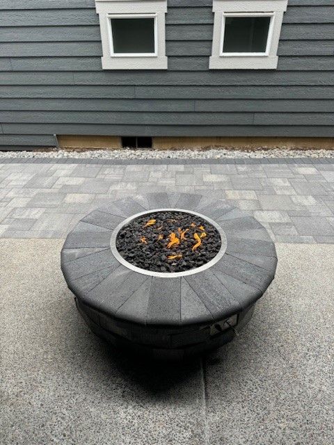 A fire pit is sitting on a patio in front of a house