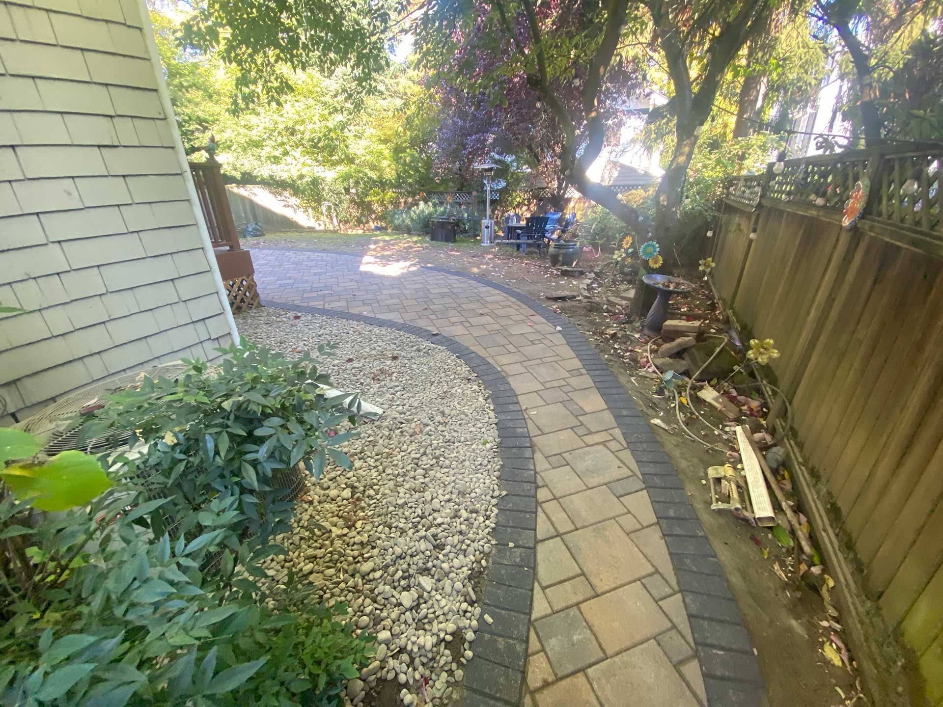 a walkway leading to a house with a fence in the background