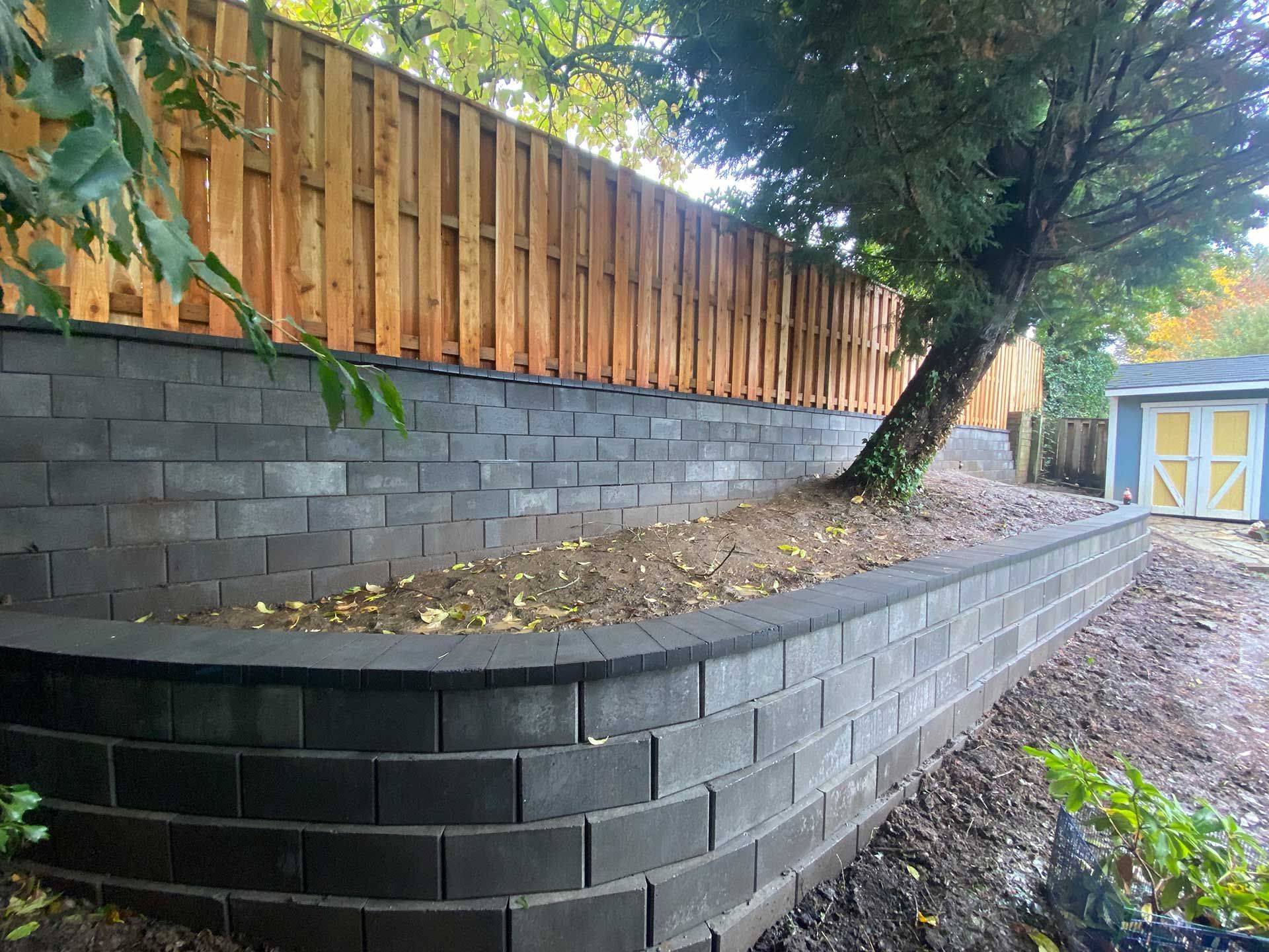 a retaining wall with a wooden fence behind it