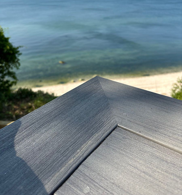 Gray rooftop overlooking a sandy beach and calm blue ocean on a clear day