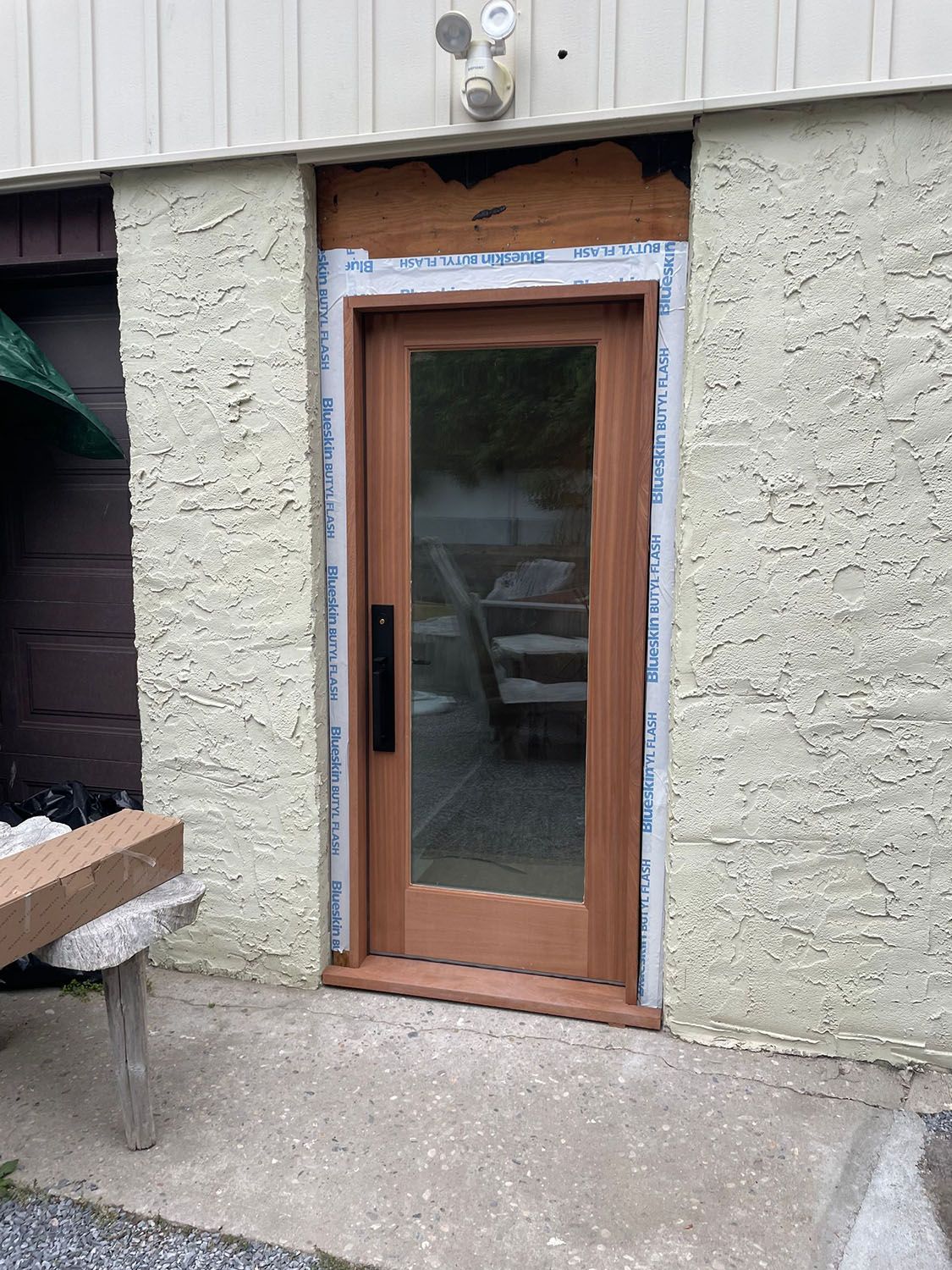 Wood-framed glass door set in a stucco exterior wall with construction trim around the opening.