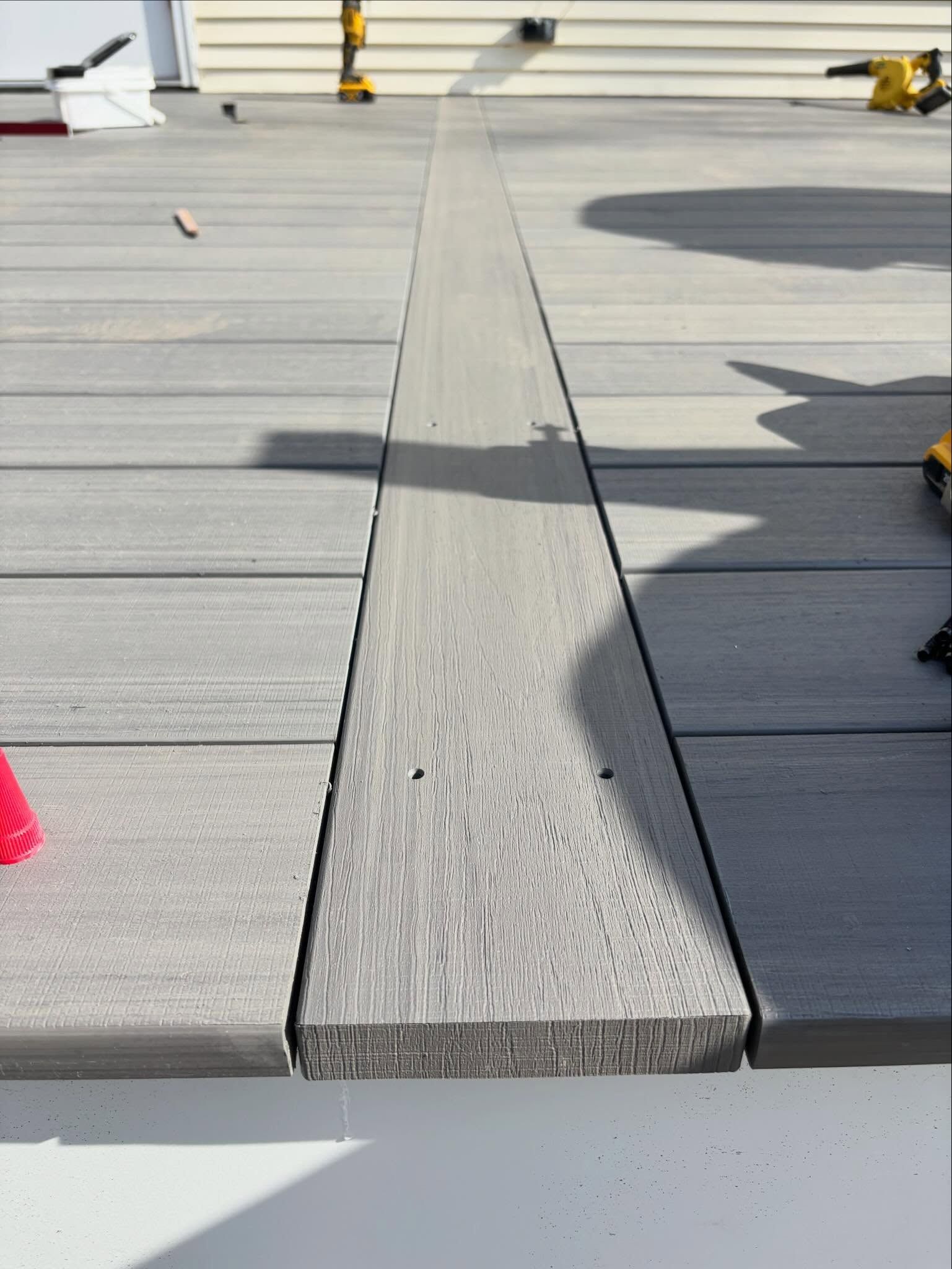 Gray rooftop with a central seam and small yellow and red markers, viewed in bright sunlight